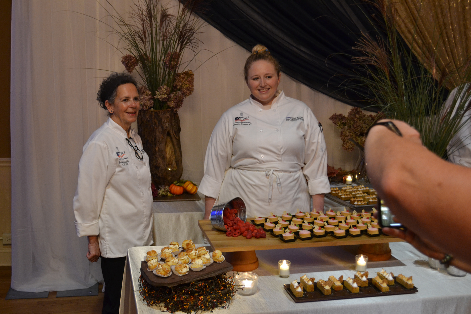 Guest Chefs Sue Hatalsky and Vanessa Traver standing in front of table of desserts