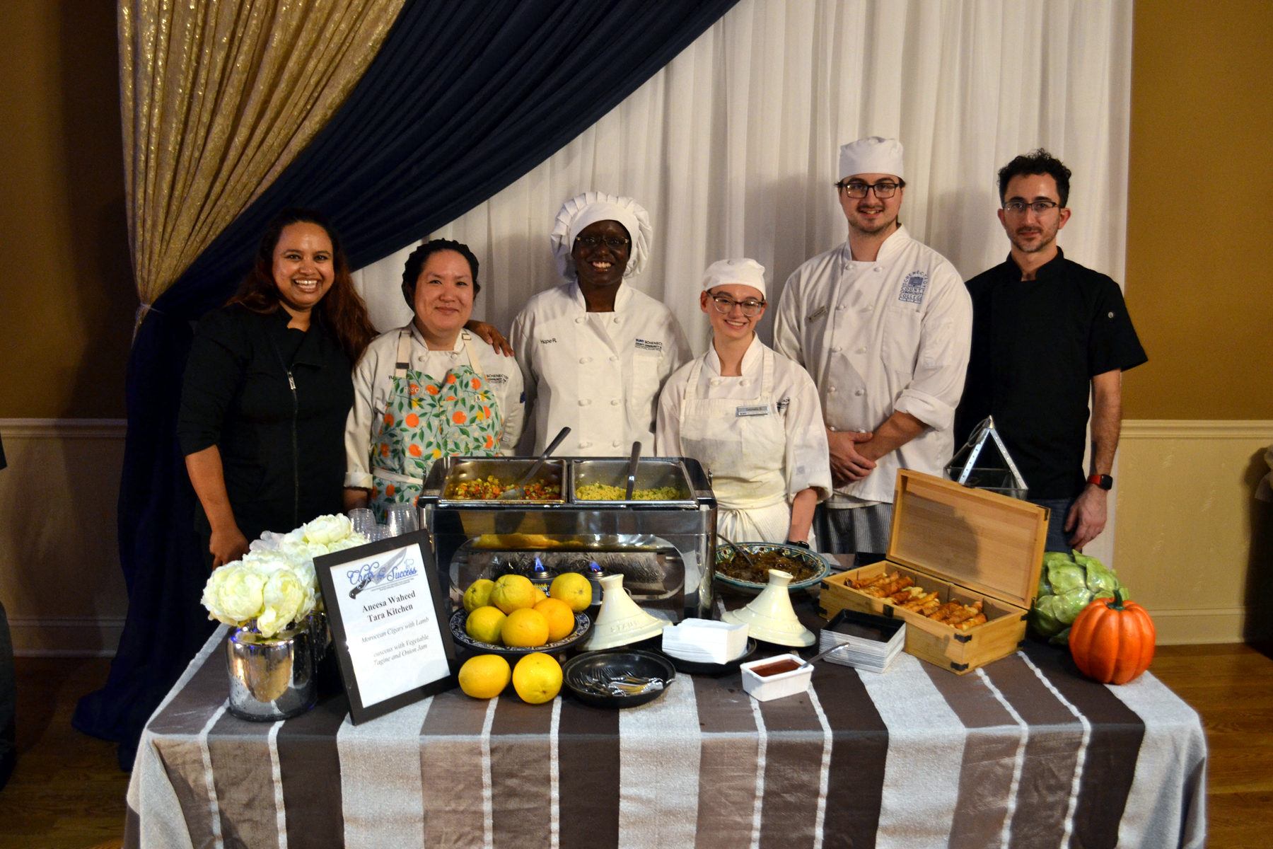 Guest Chef Aneesa Waheed with alumni and students in front of table with food