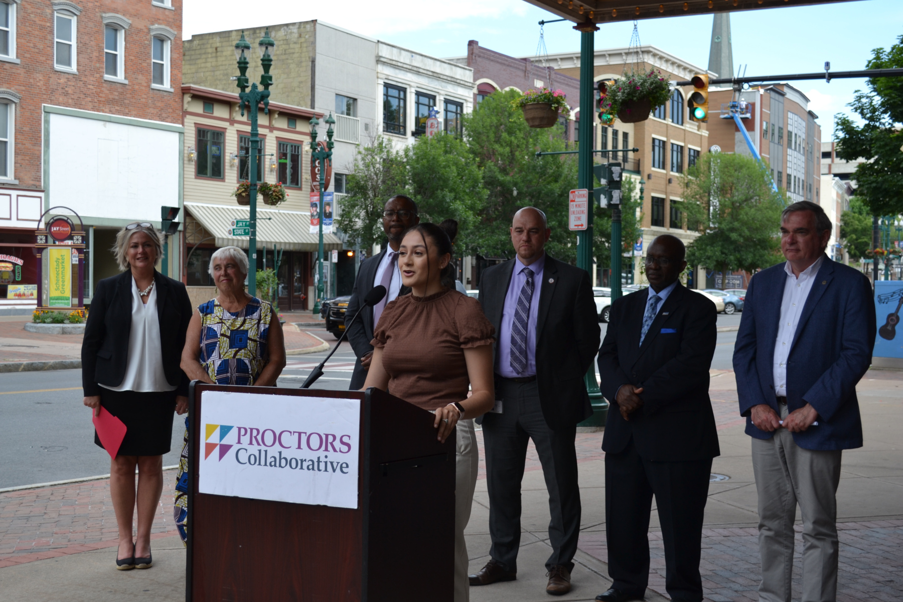 Emelyn Martinez speaking at podium under Proctors marquee.