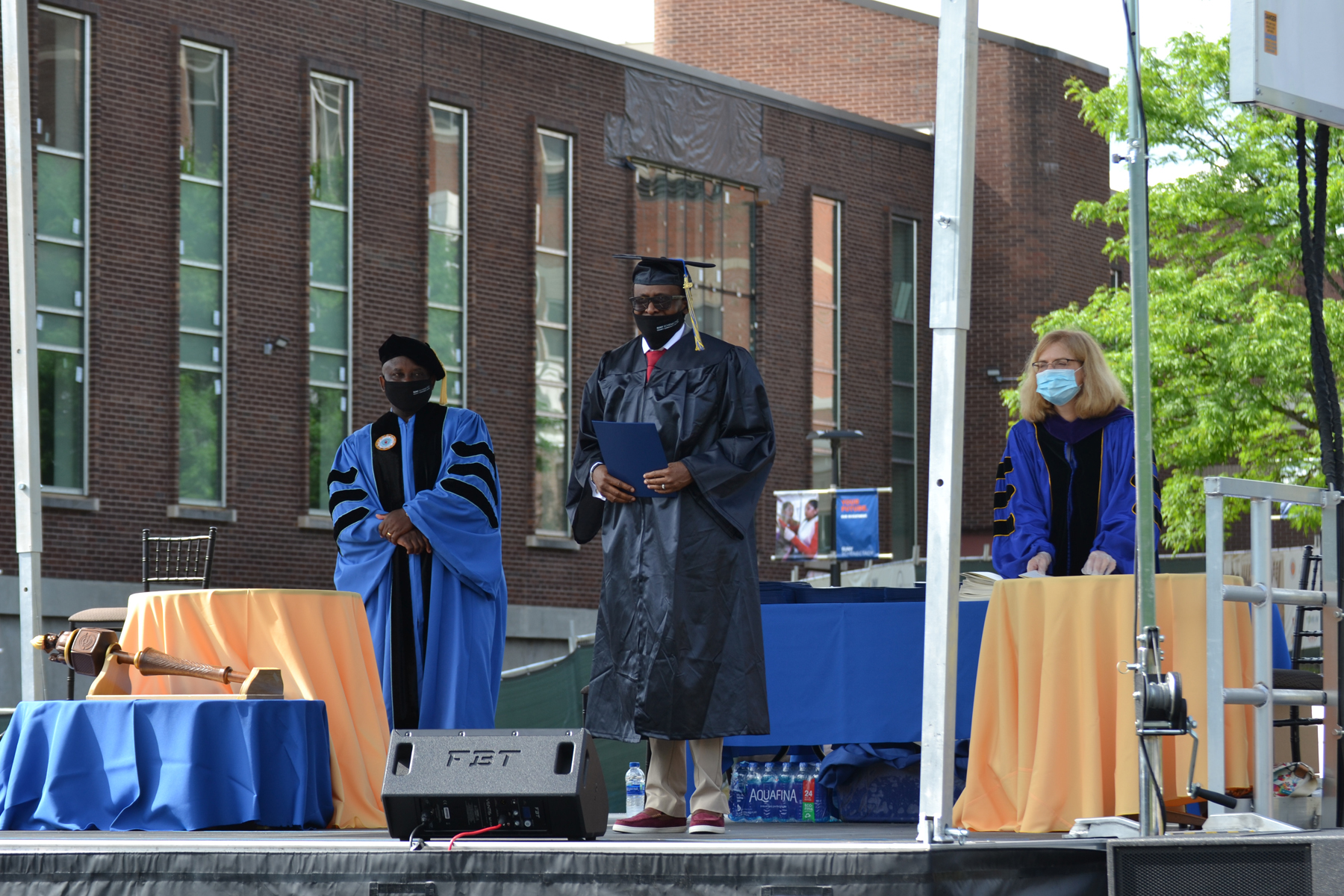 Graduate Olujide Adesina holding up diploma on stage