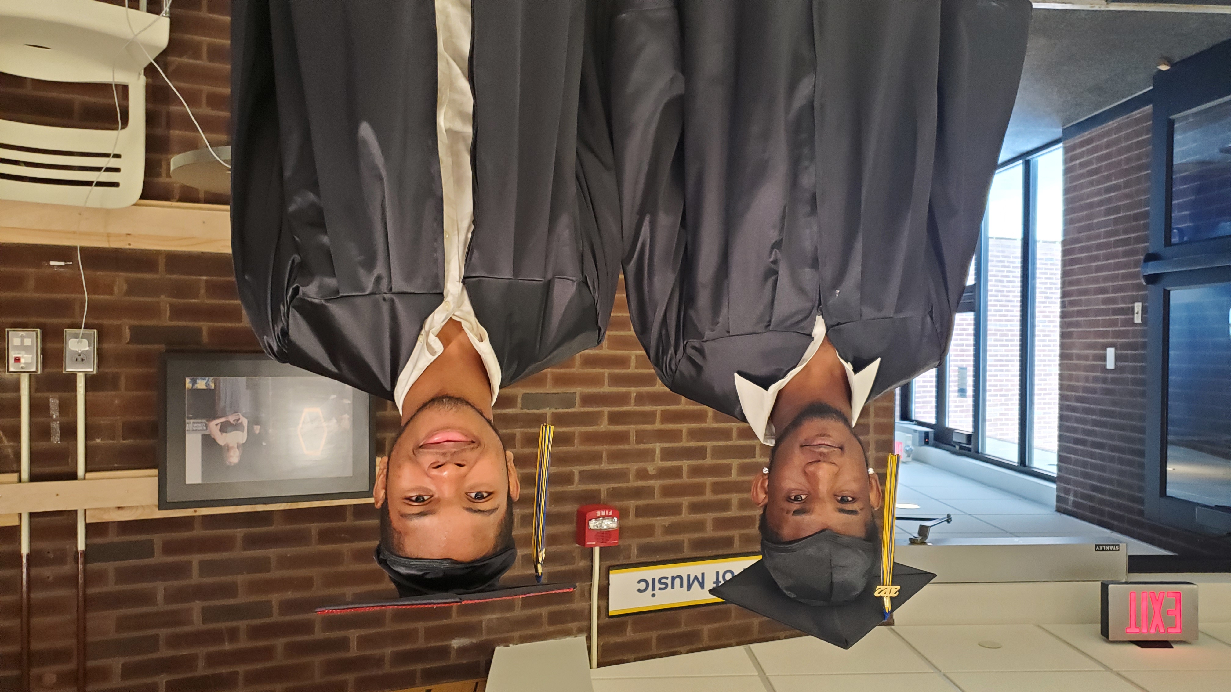 Two male graduates standing inside smiling