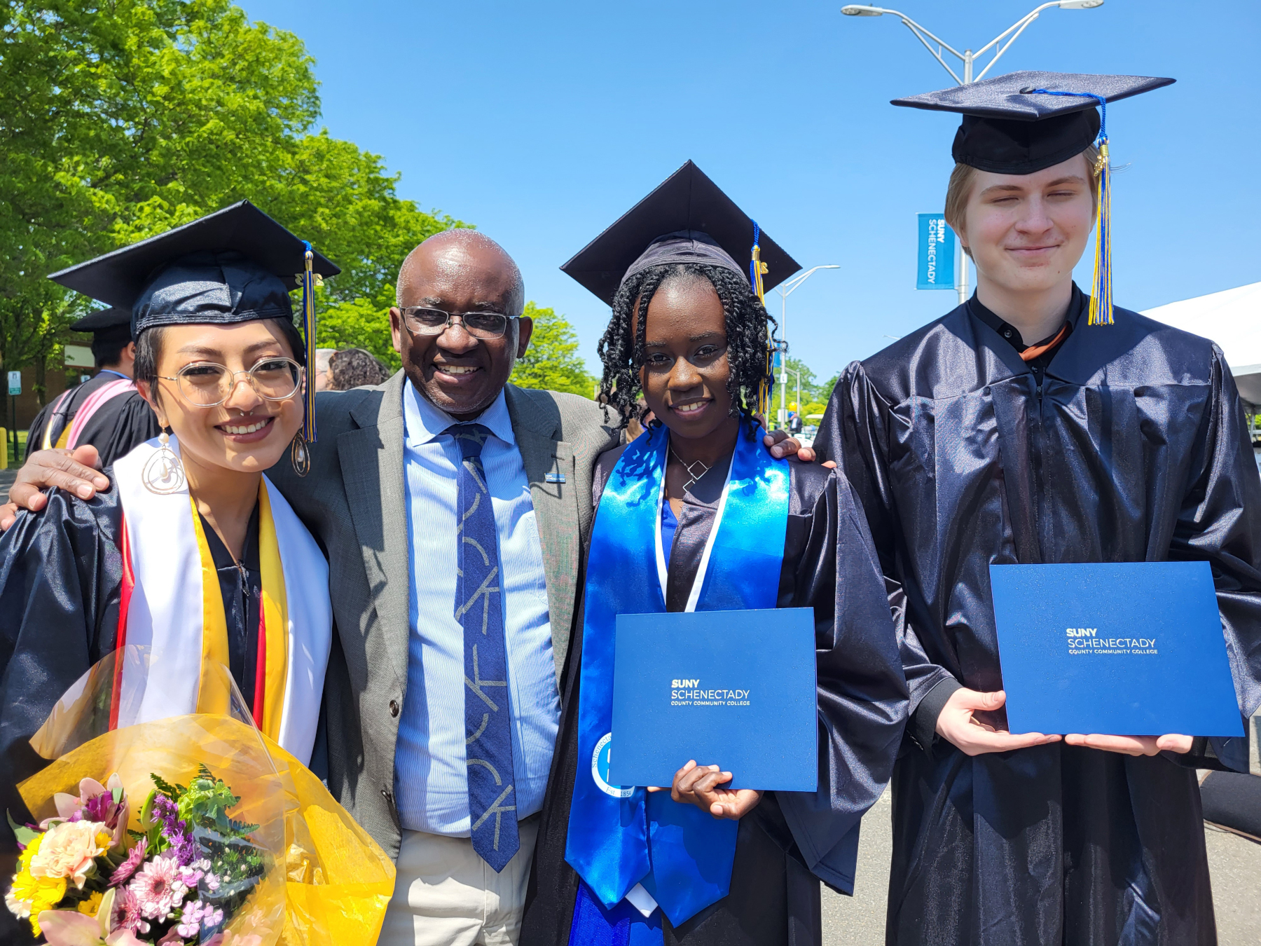 Dr. Moono standing with graduates, smiling