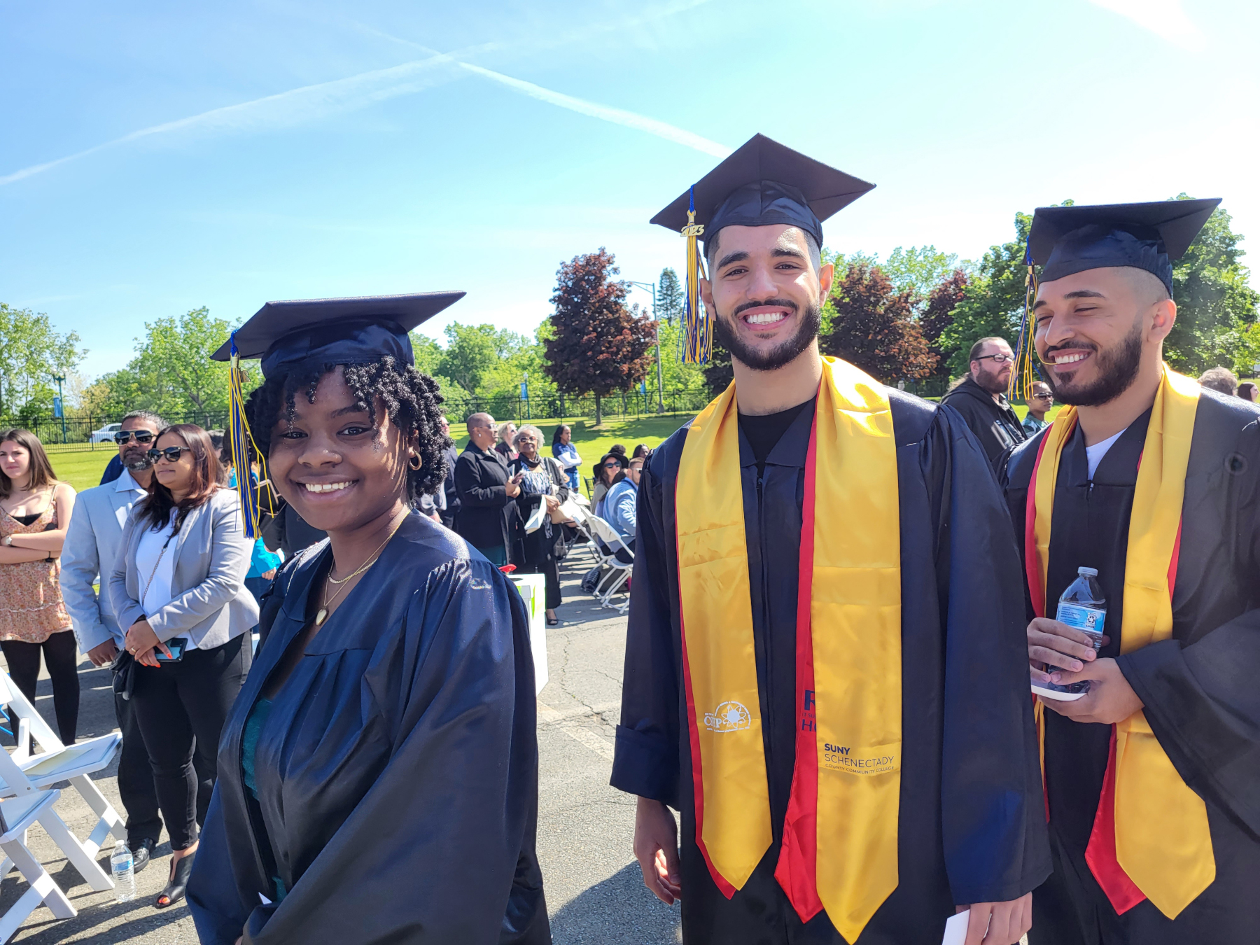 Graduates walking in line outside, smiling