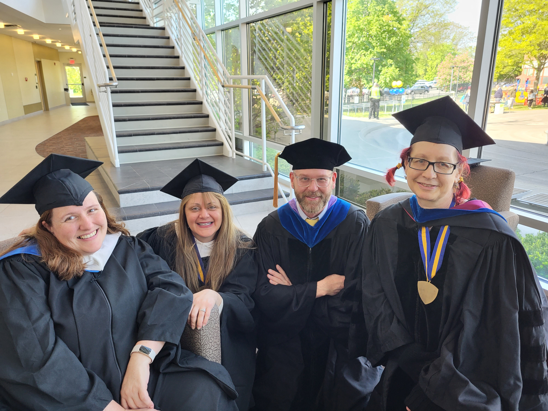 Faculty in regalia, seated, smilng