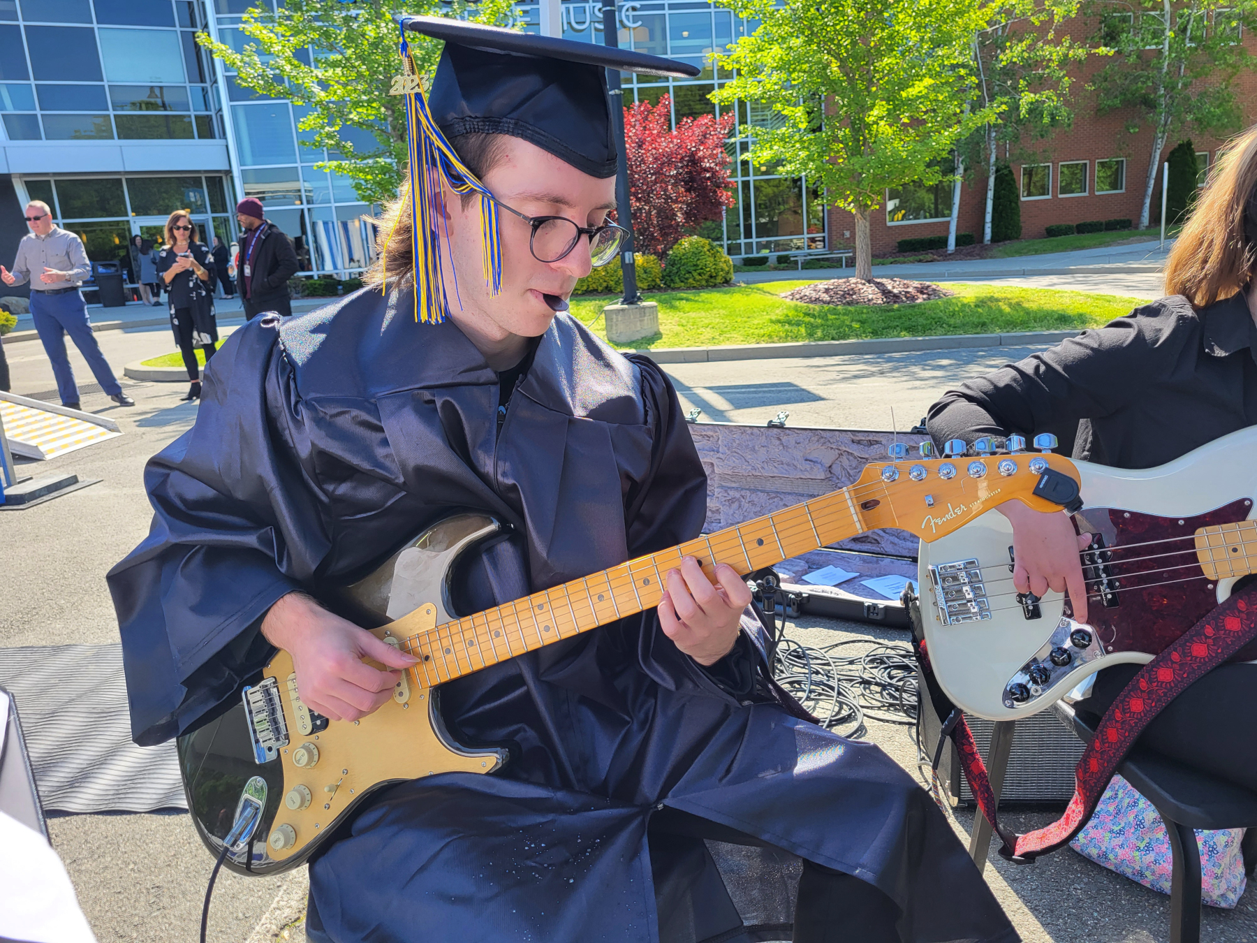 Graduate in cap and gown, playing guitar