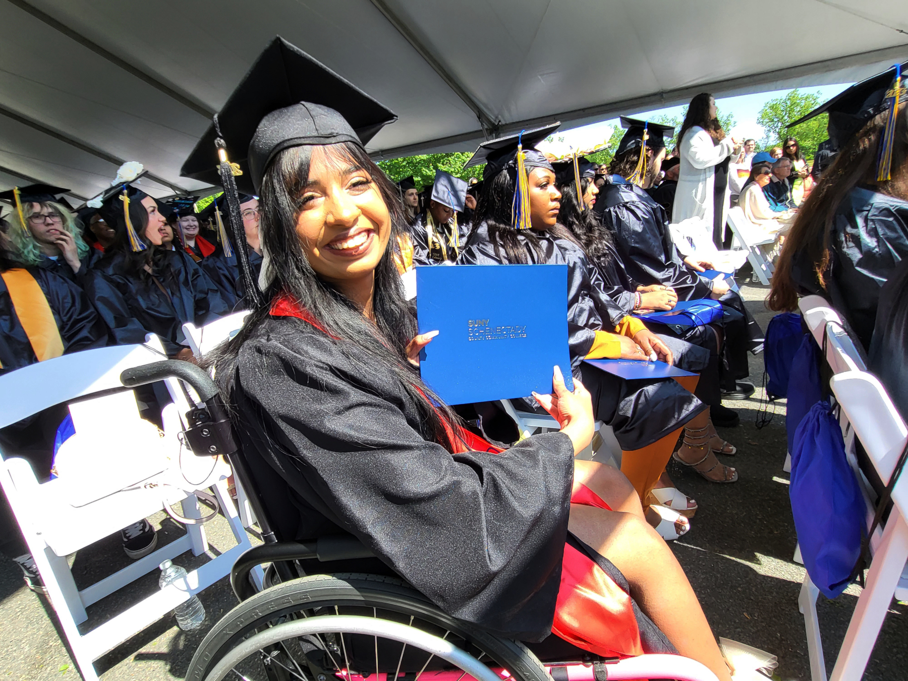 Graduate holding degree, smiling