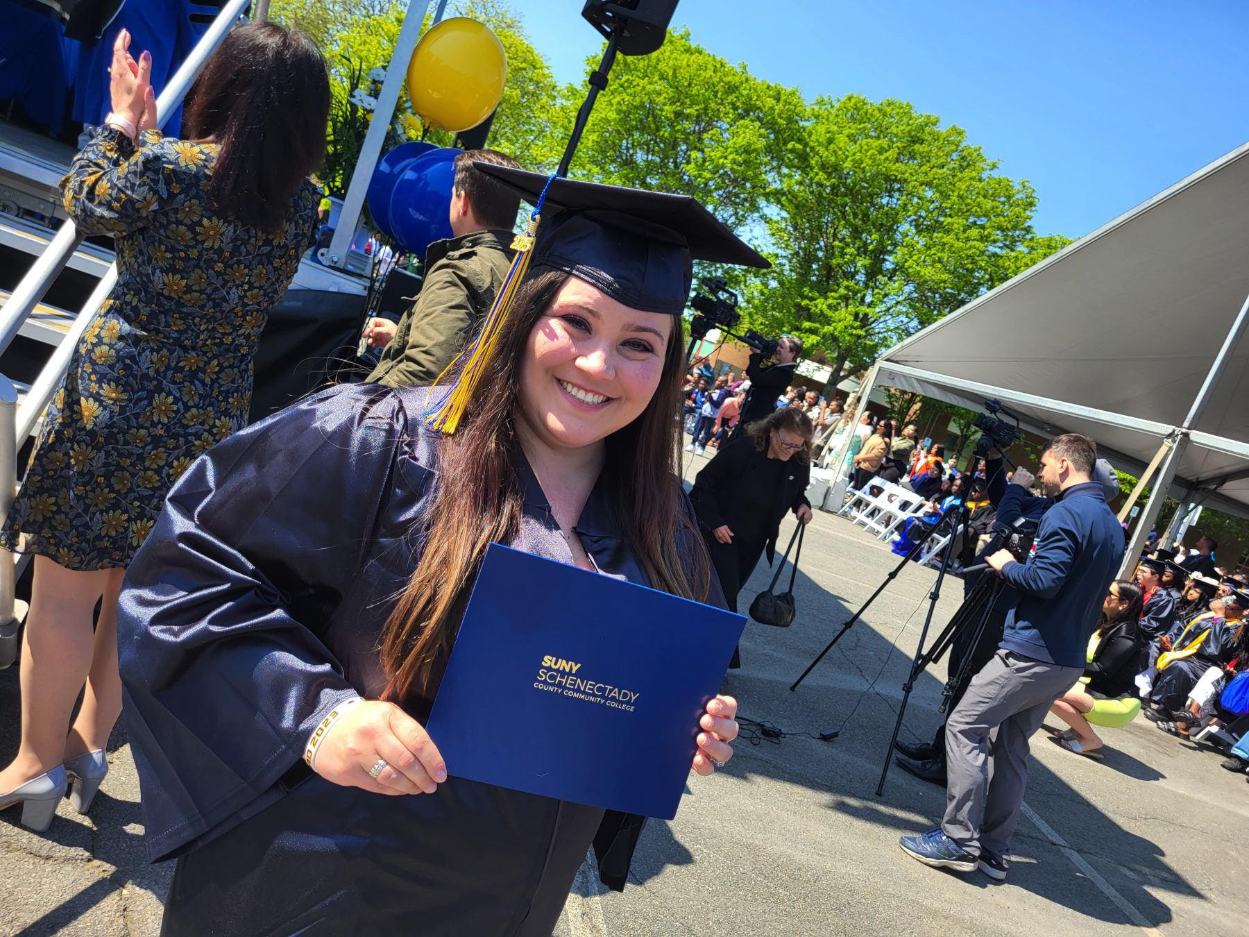 Graduate holding degree, coming off stage, smiling