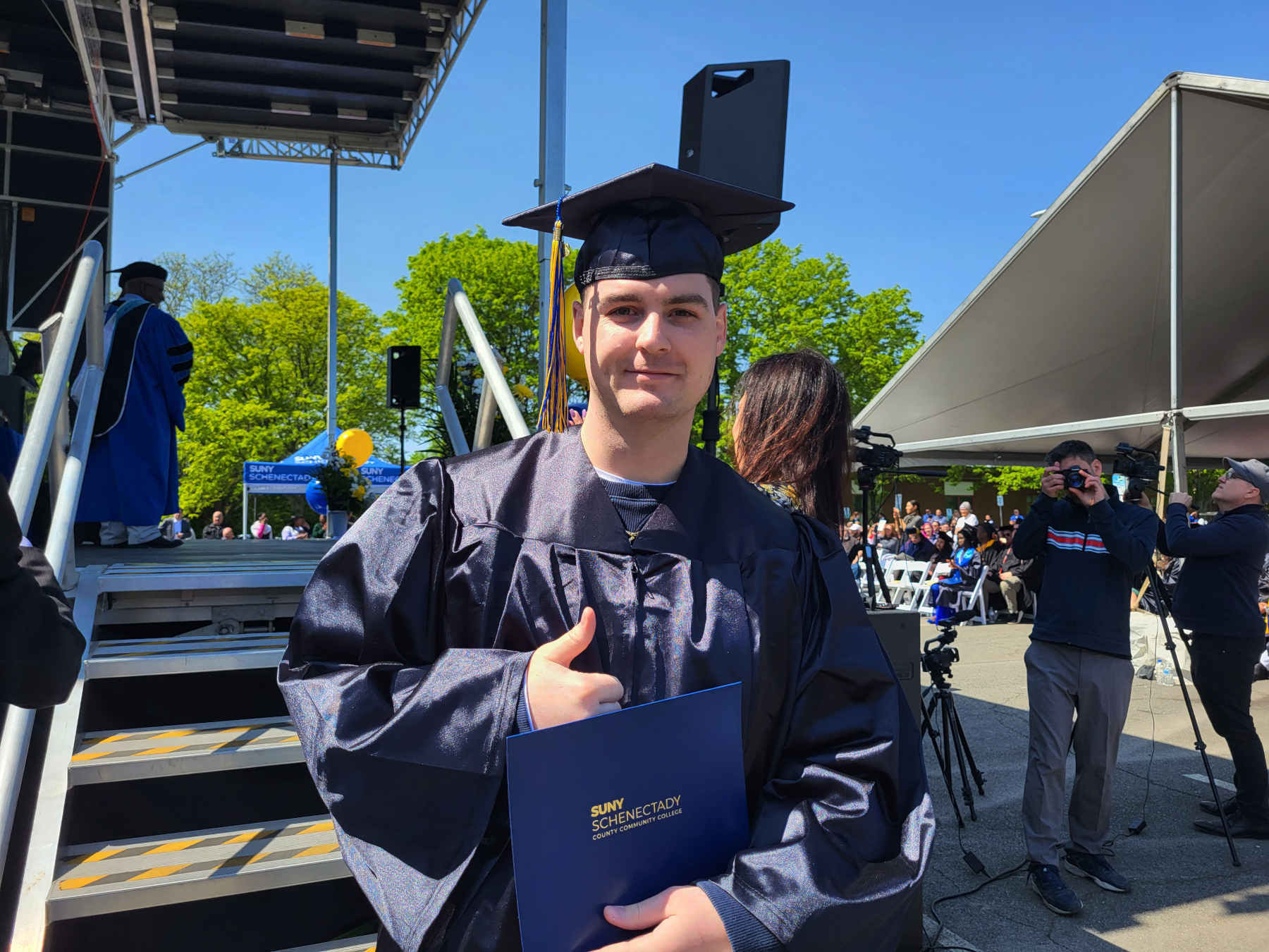 Graduate holding degree, coming off stage, smiling