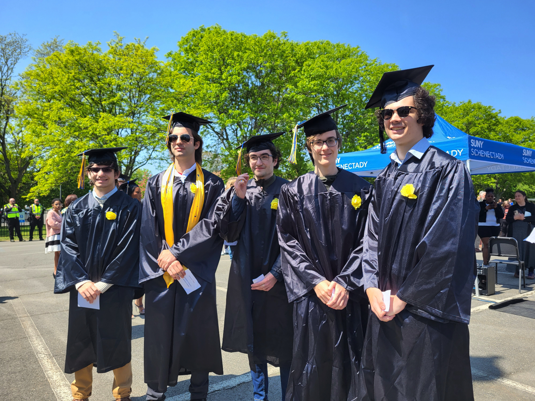 Five graduates in line, smiling, waiting to cross the stage