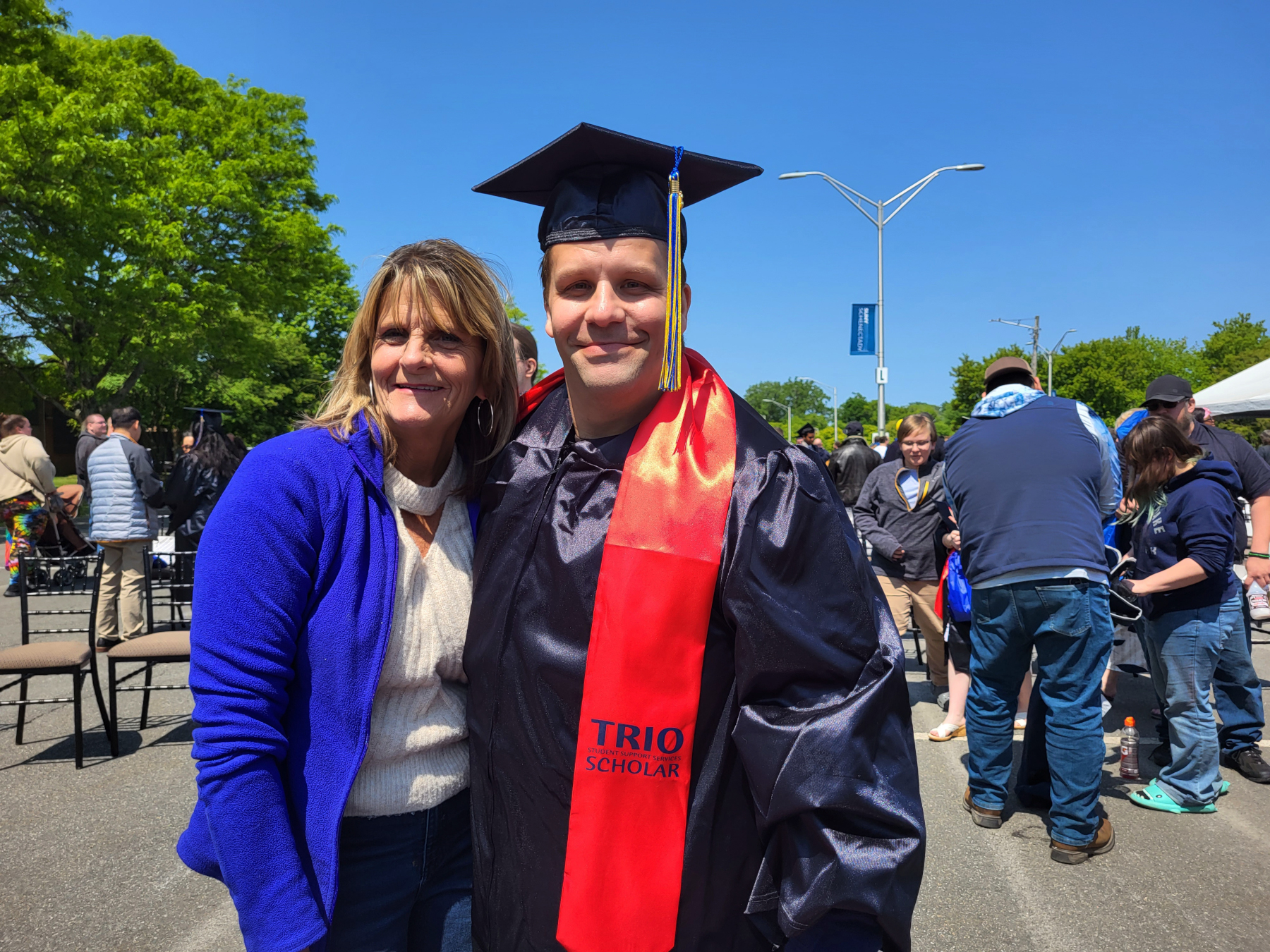Graduate and family member, standing, smiling outside