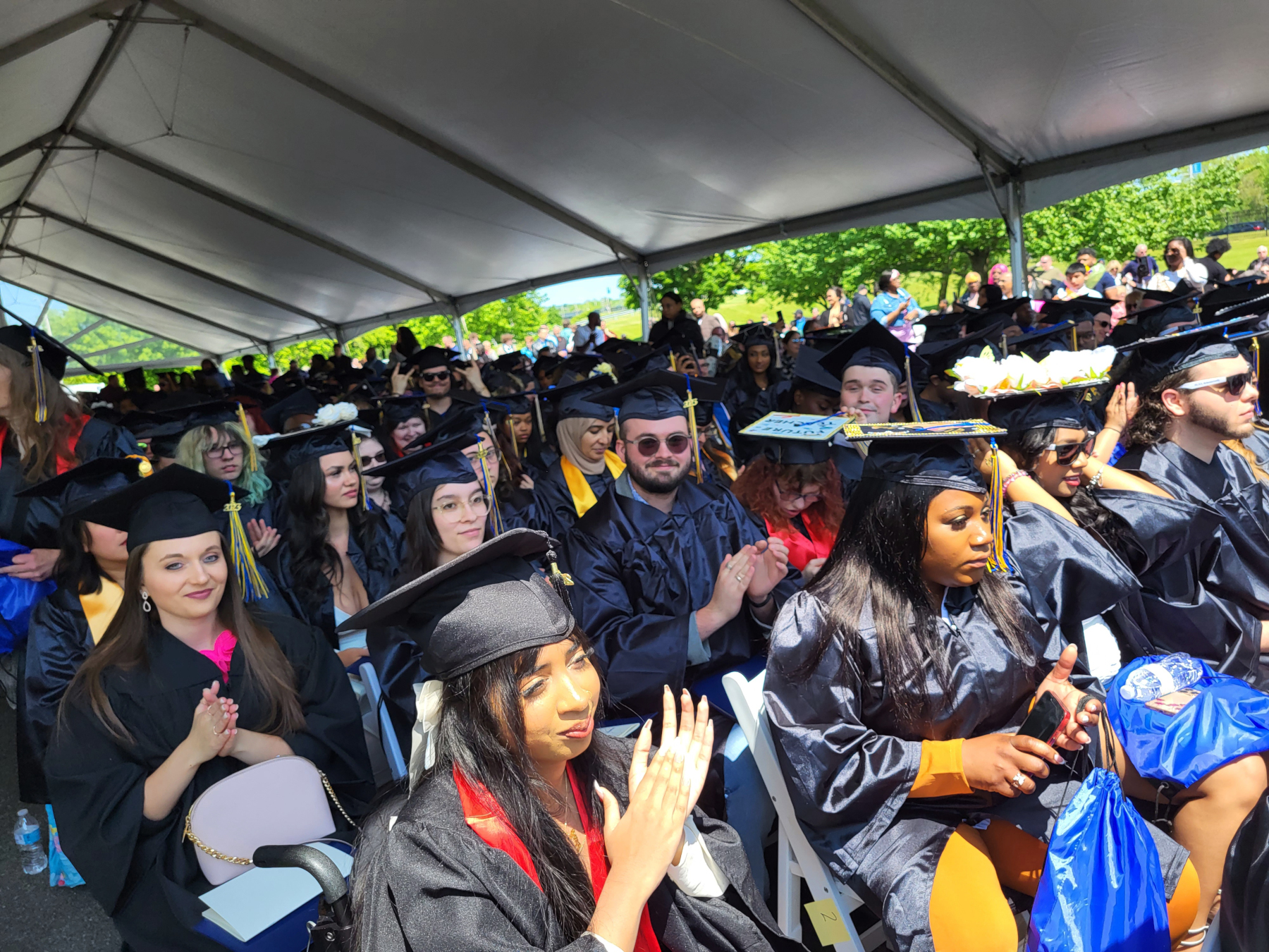Graduates sitting under tent clapping