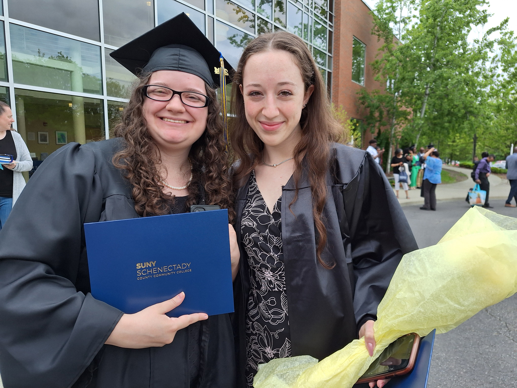 Two graduates outside the School of Music, smiling