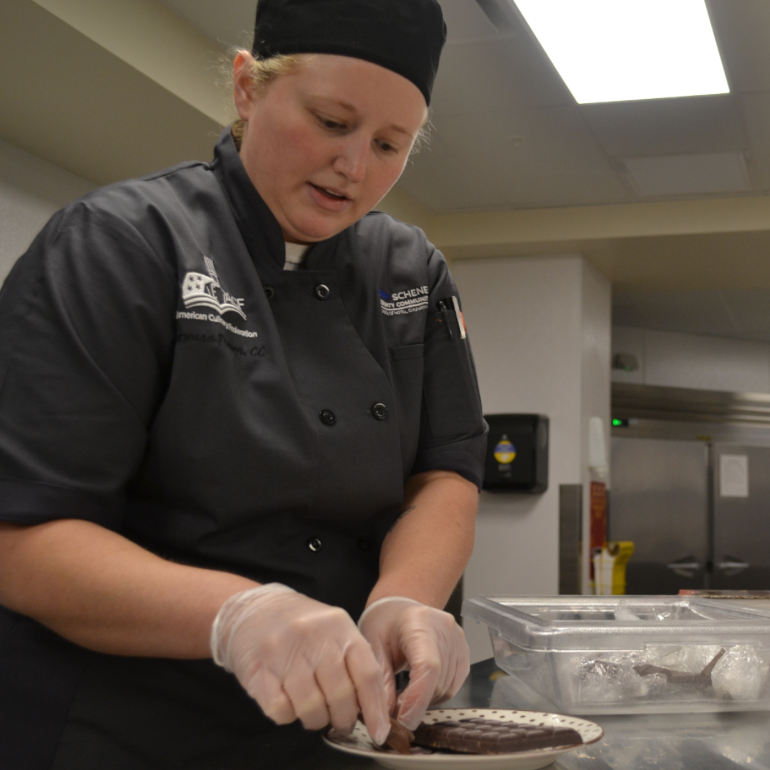 Vaness Traver, Assistant Professor, in uniform, making chocolate