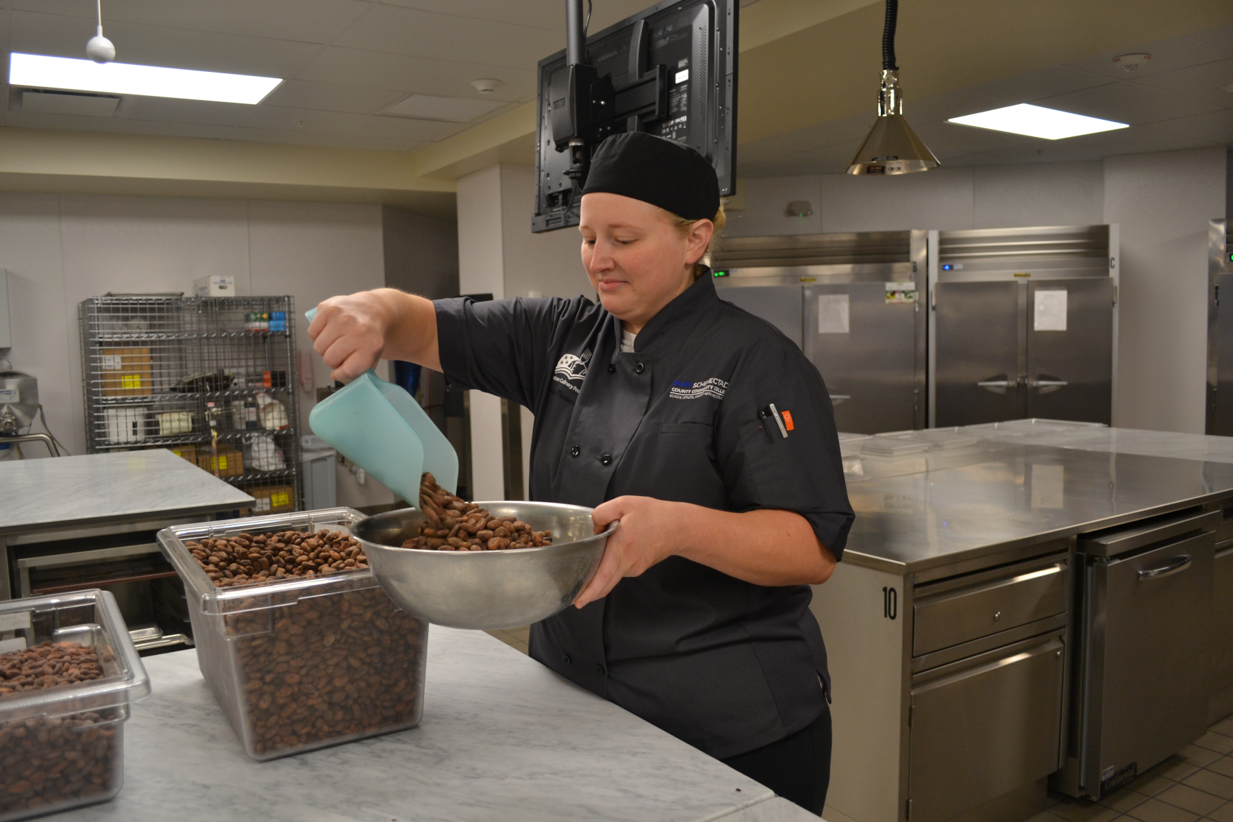 Vaness Traver in new Confection Lab scooping cocoa beans into bowl