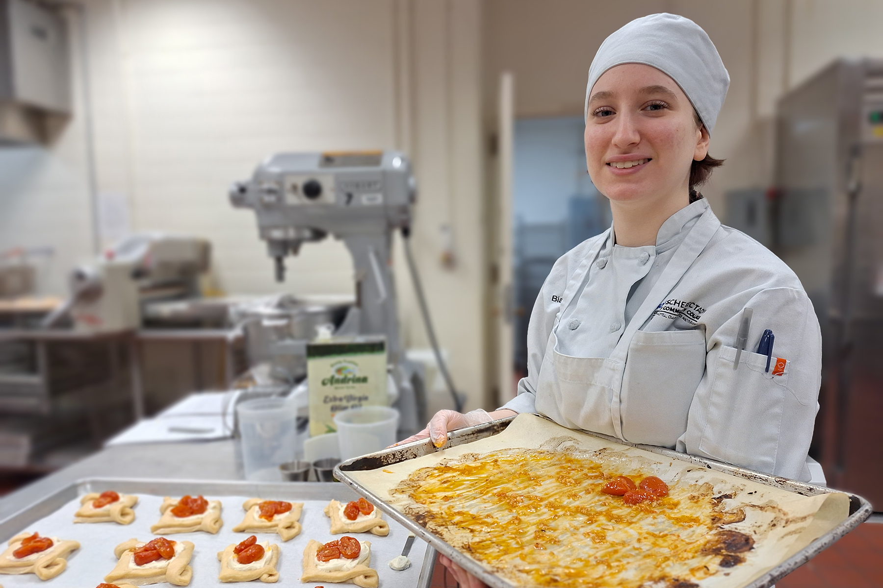 Student in uniform holding tray of baked goods