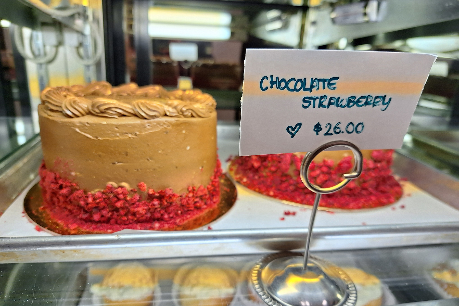 Chocolate strawberry cake inside glass case in bakery