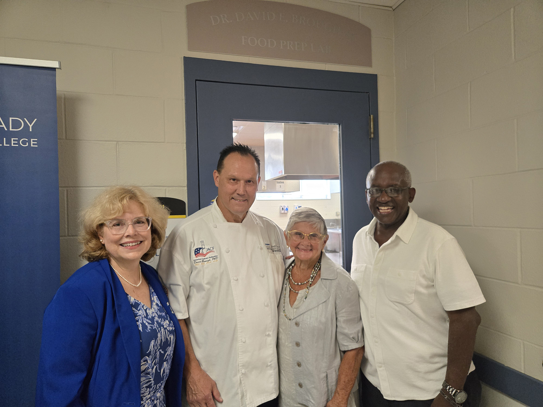 Ann Fleming Brown, Dr. David Brough, Joan Dembinski, and Dr. Steady Moono, smiling, standing outside Brough Culinary Arts Lab