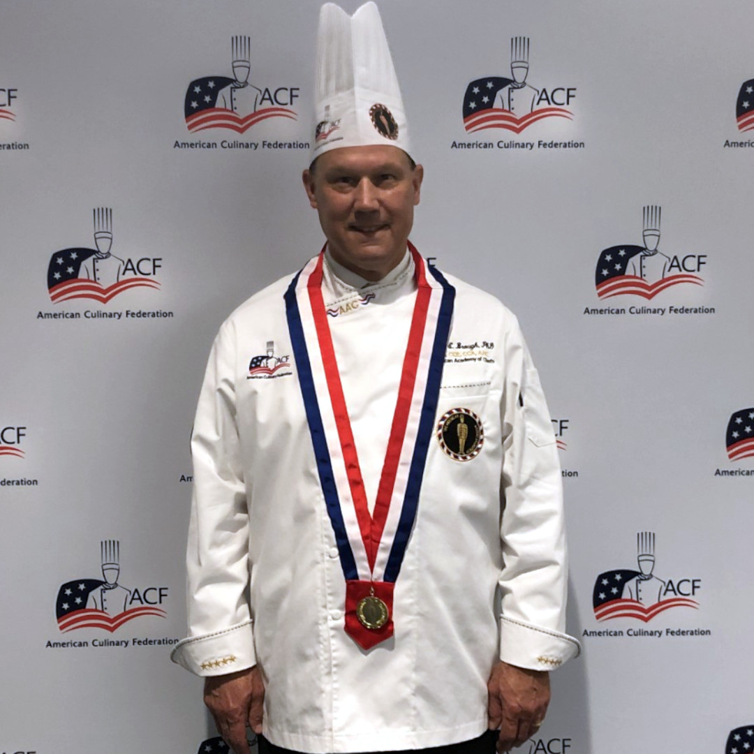 Dr. David Brough in chef's uniform wearing medallion at AAC Induction Dinner.