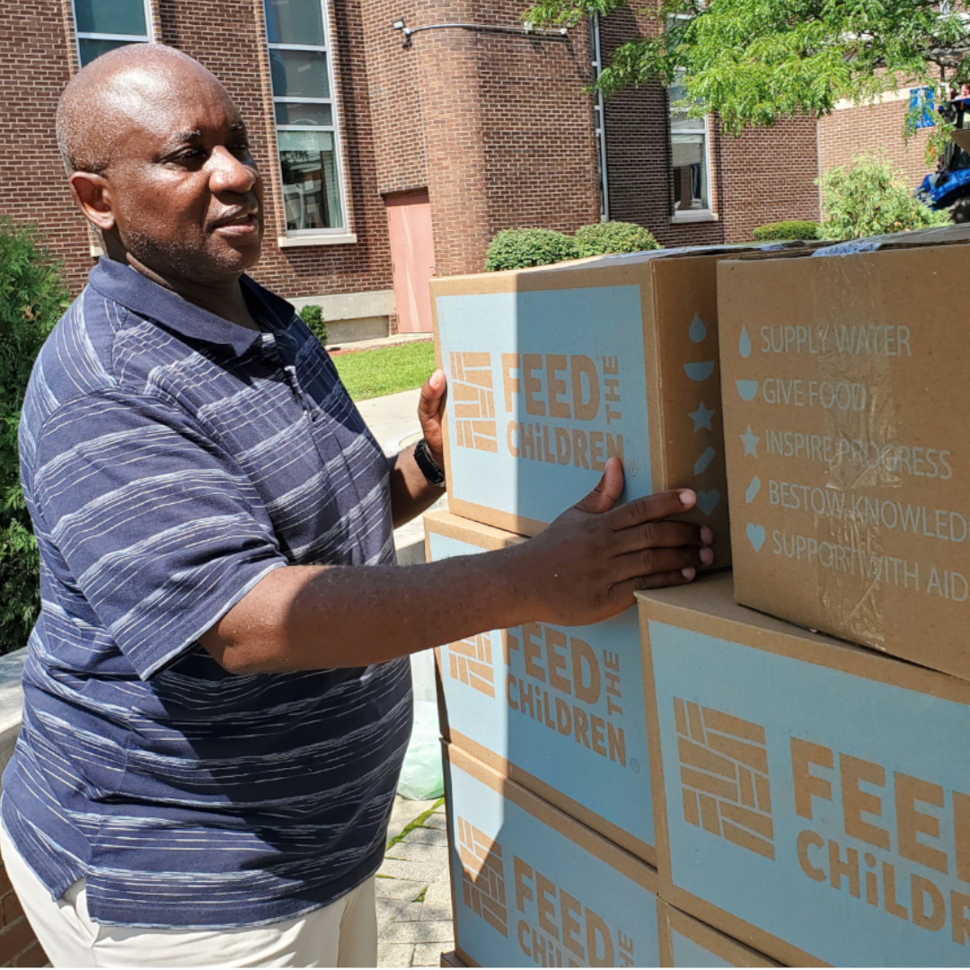 Dr. Moono lifting boxes during Feed The Children food giveaway