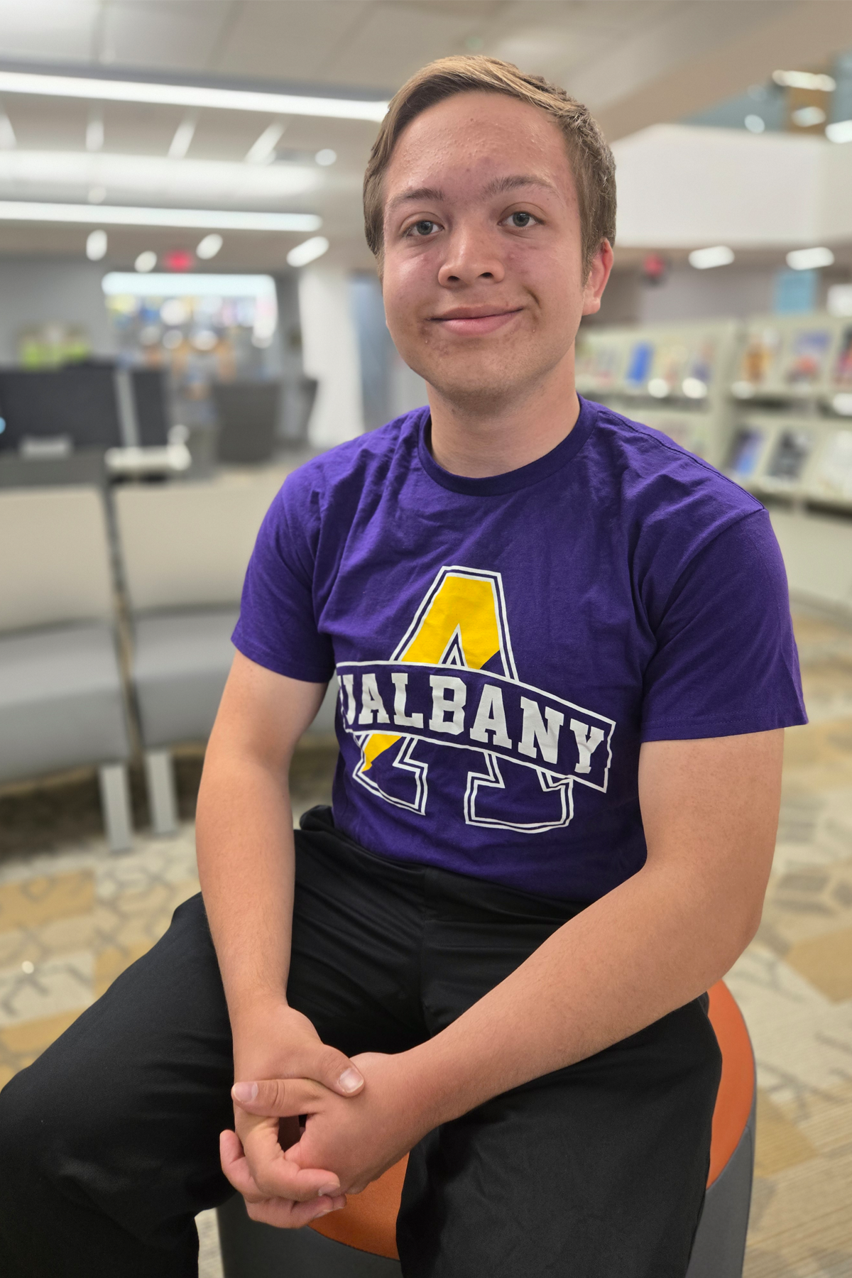 Dylan Slater, smiling, seated in Learning Commons