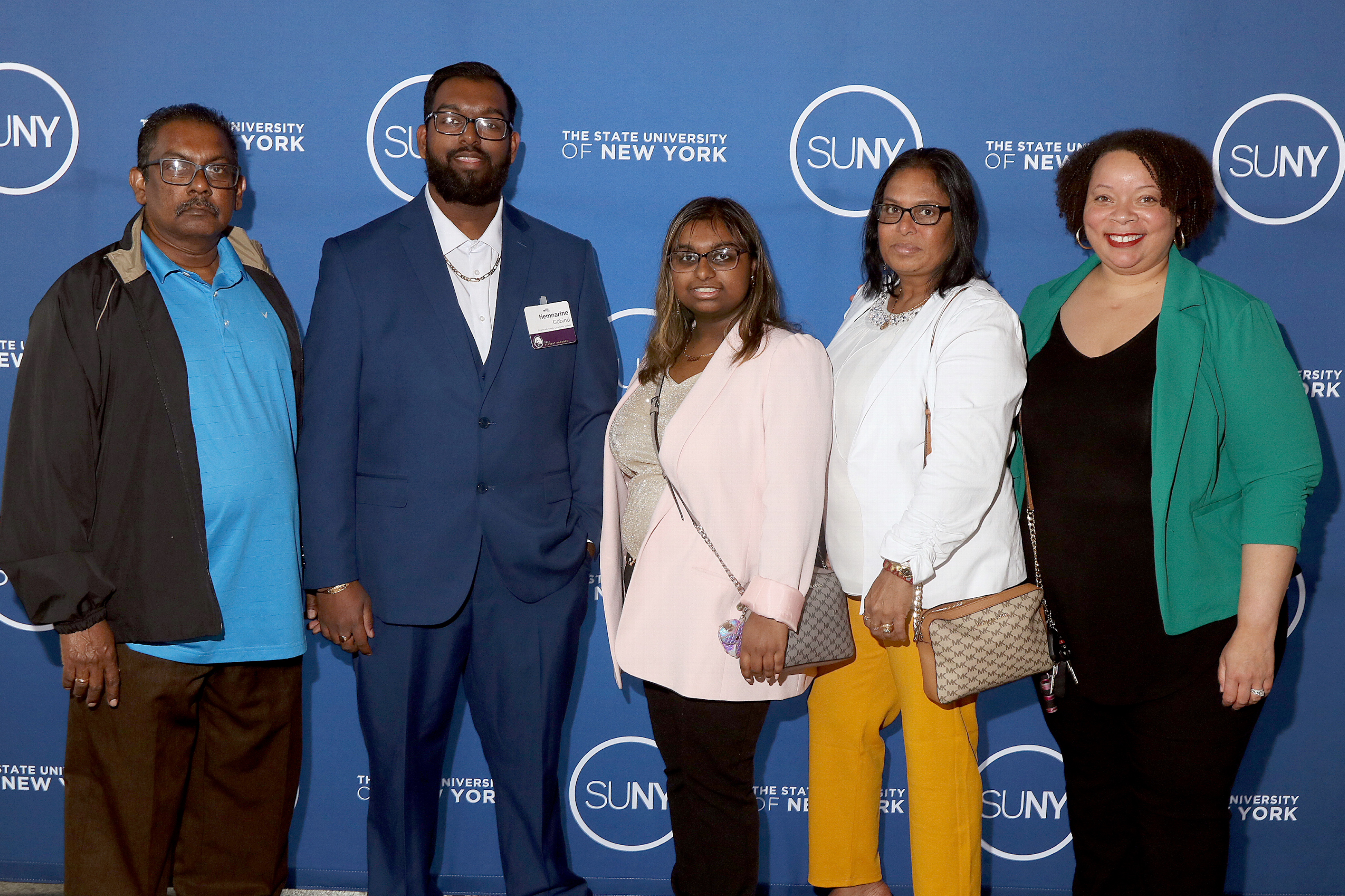 Hemnarine Gobind standing, smiling with his family and Tiombe Farley after accepting award