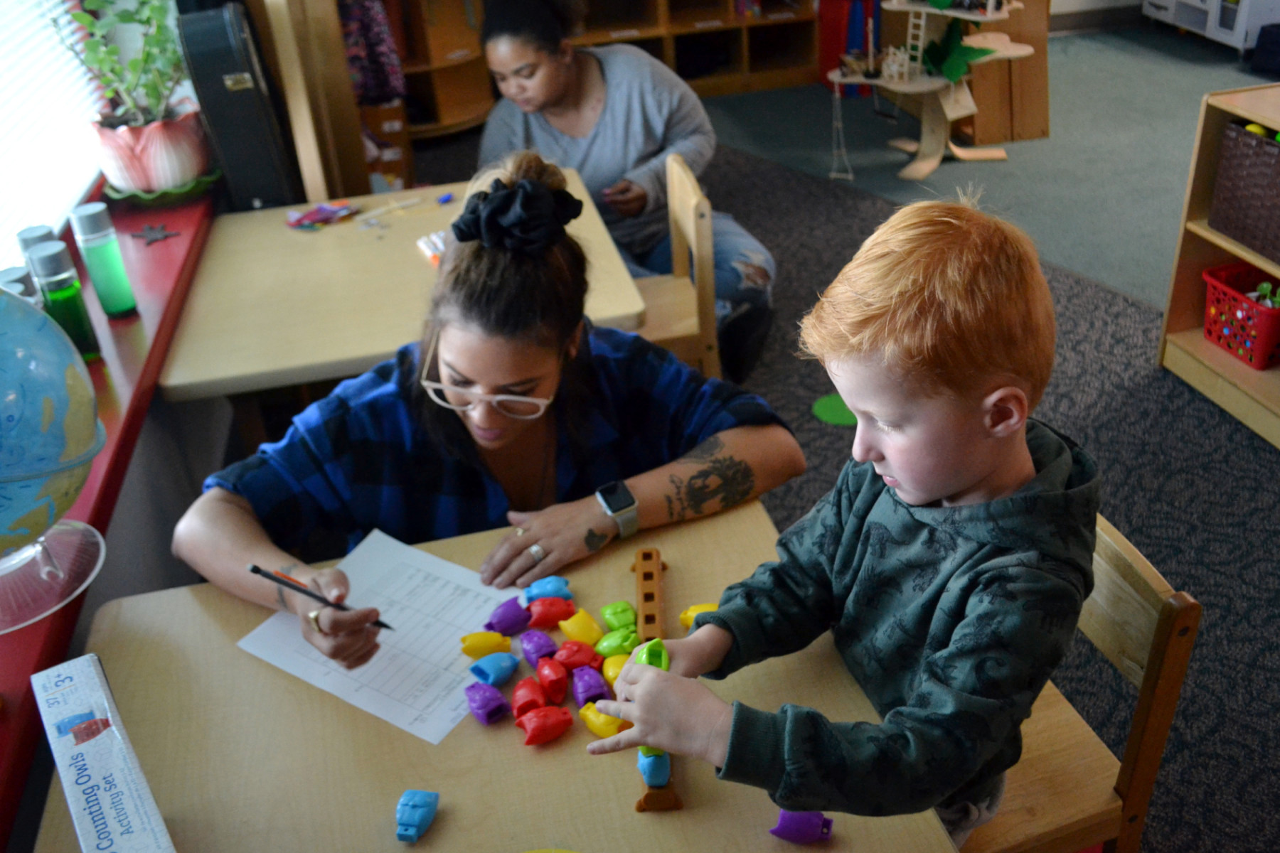 Emylie Montalvo and child seated at table counting owl toys
