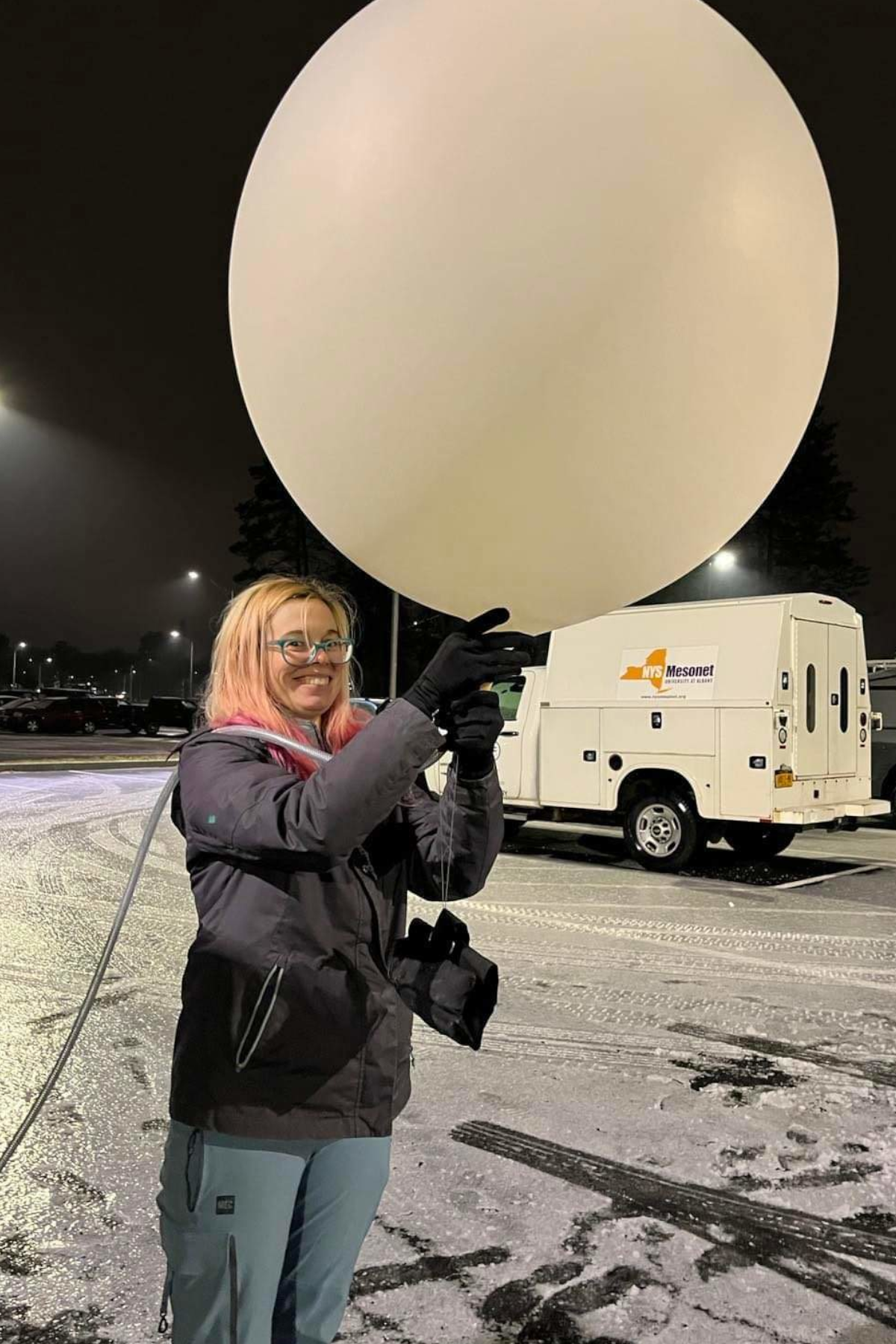 Erin Potter holding large white weather balloon, outside, smiling