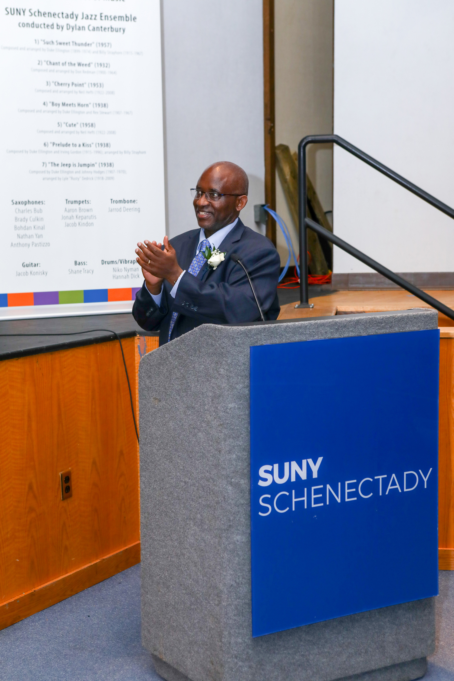 Dr. Moono smiling, speaking at podium in auditorium