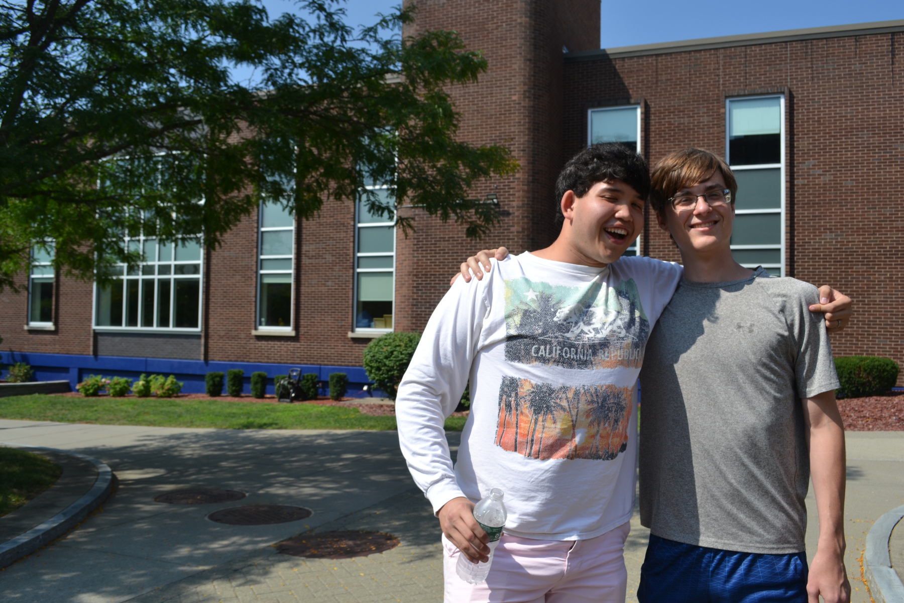 Two students smiling, standing on quad