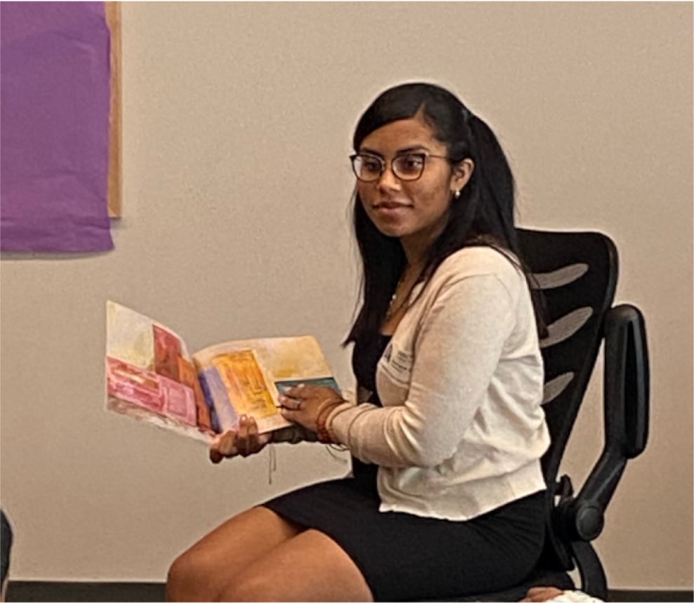 Gabriella Jones sitting down in classroom reading to students