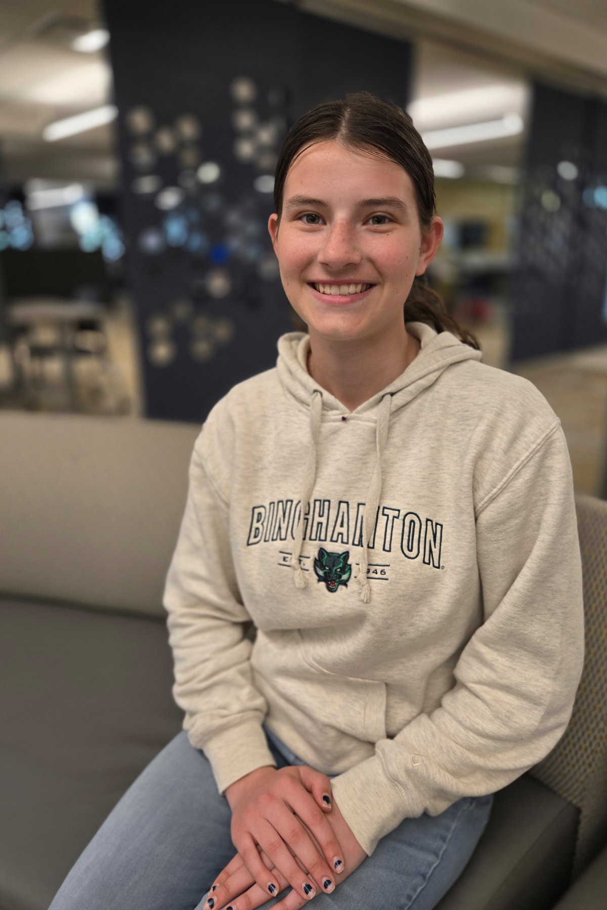Grace Van Baaren, smiling, seated in Learning Commons