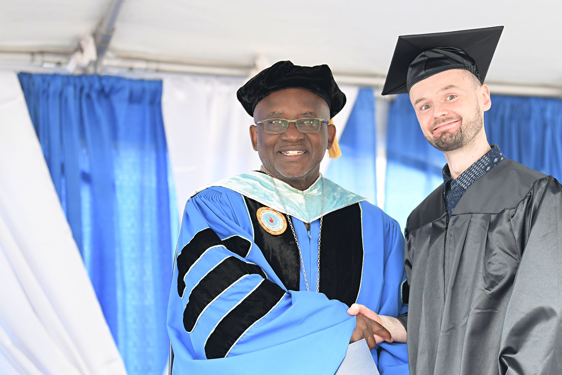Graduate on stage shaking hands with Dr. Moono
