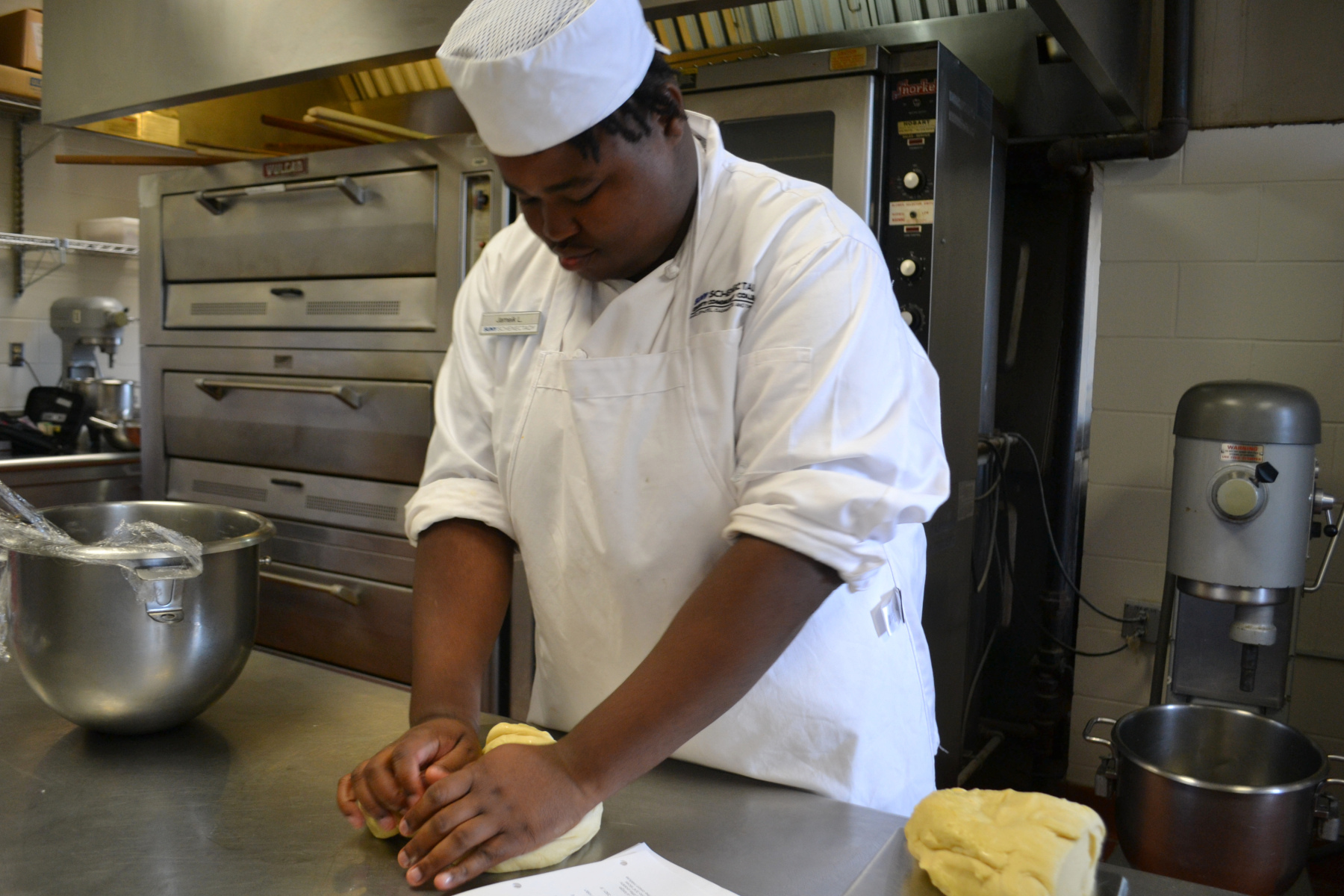 Student kneading dough, making bread in Baking Lab