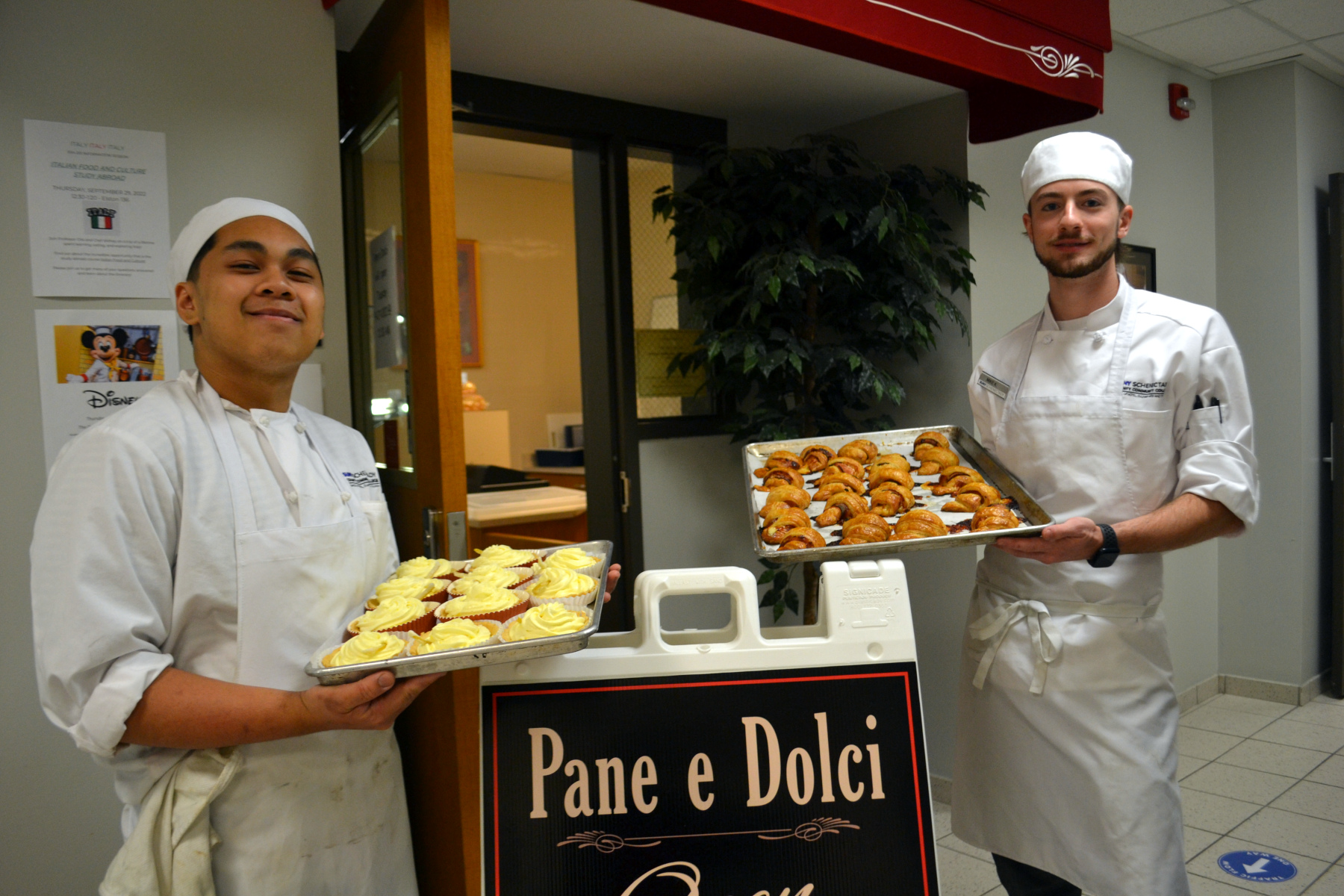 Students holding trays of baked goods standing in front of Pane e Dolci bakery,.