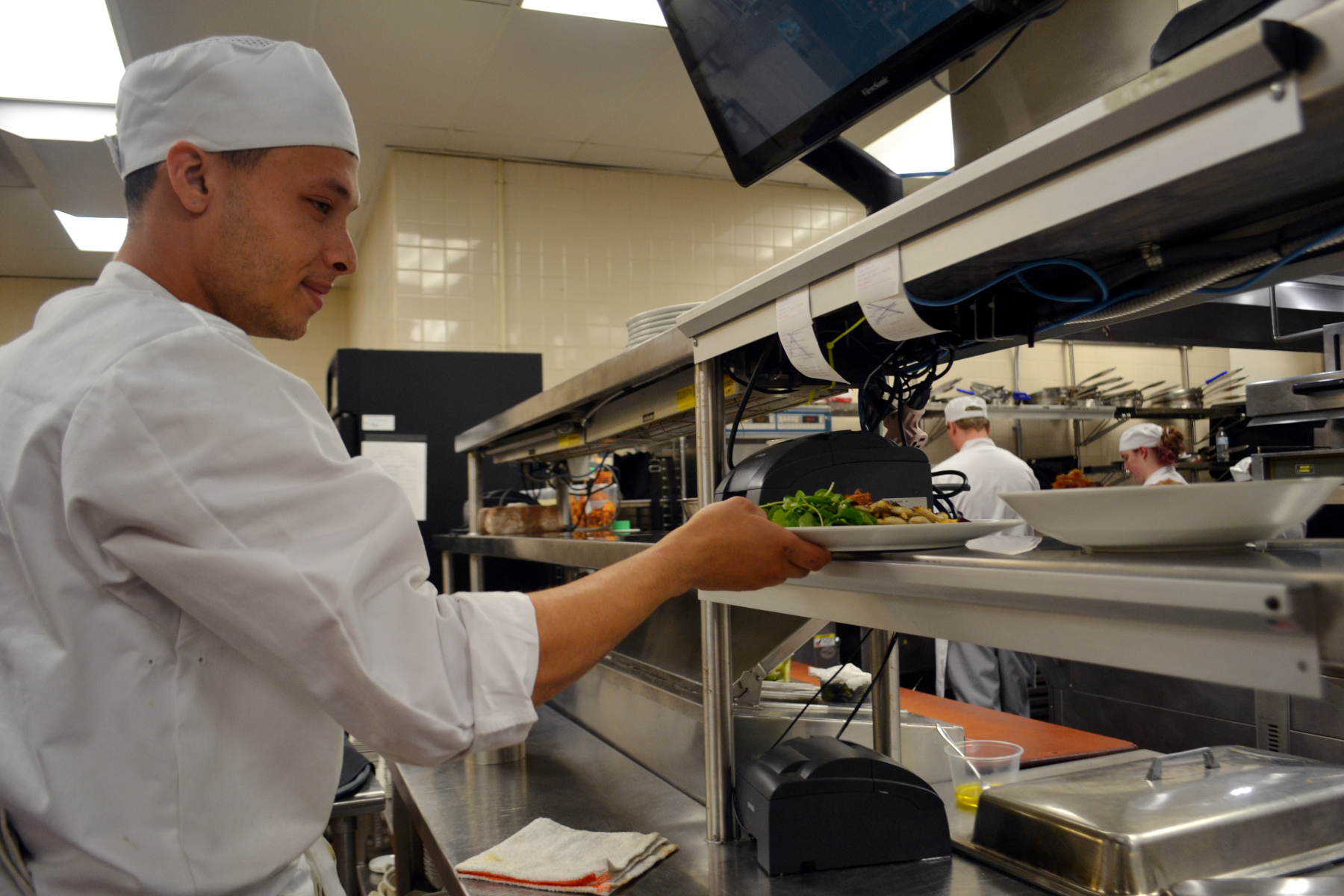 Christian Dobert in Culinary Arts Lab reaching for plate