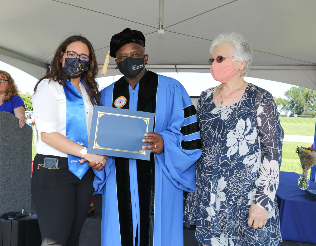 Healthcare grad on stage with Dr. Moono and Dr. Rota