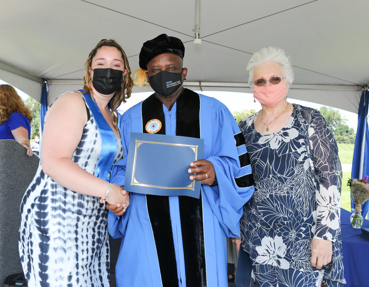 healthcare grad on stage with Dr. Moono and Dr. Rota