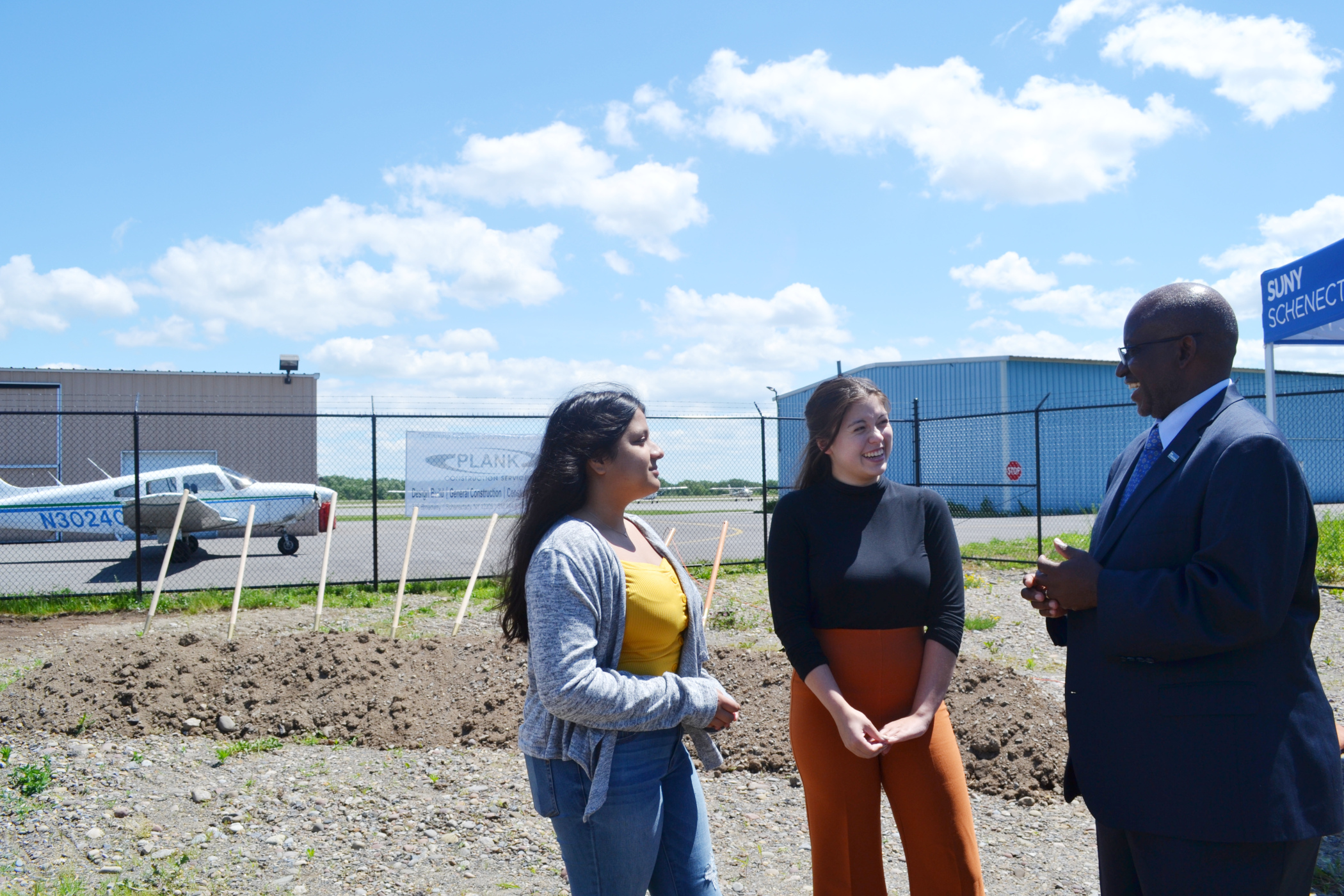 Aviation students speaking with Dr. Steady Moono with airplane behind them