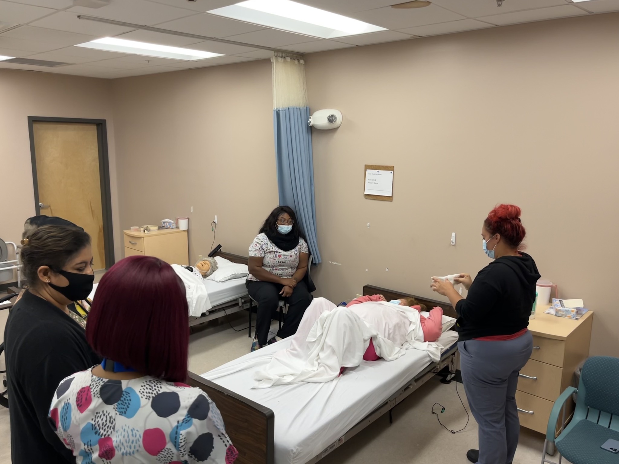 Students standing near hospital bed in health care classes in lab at Center City site