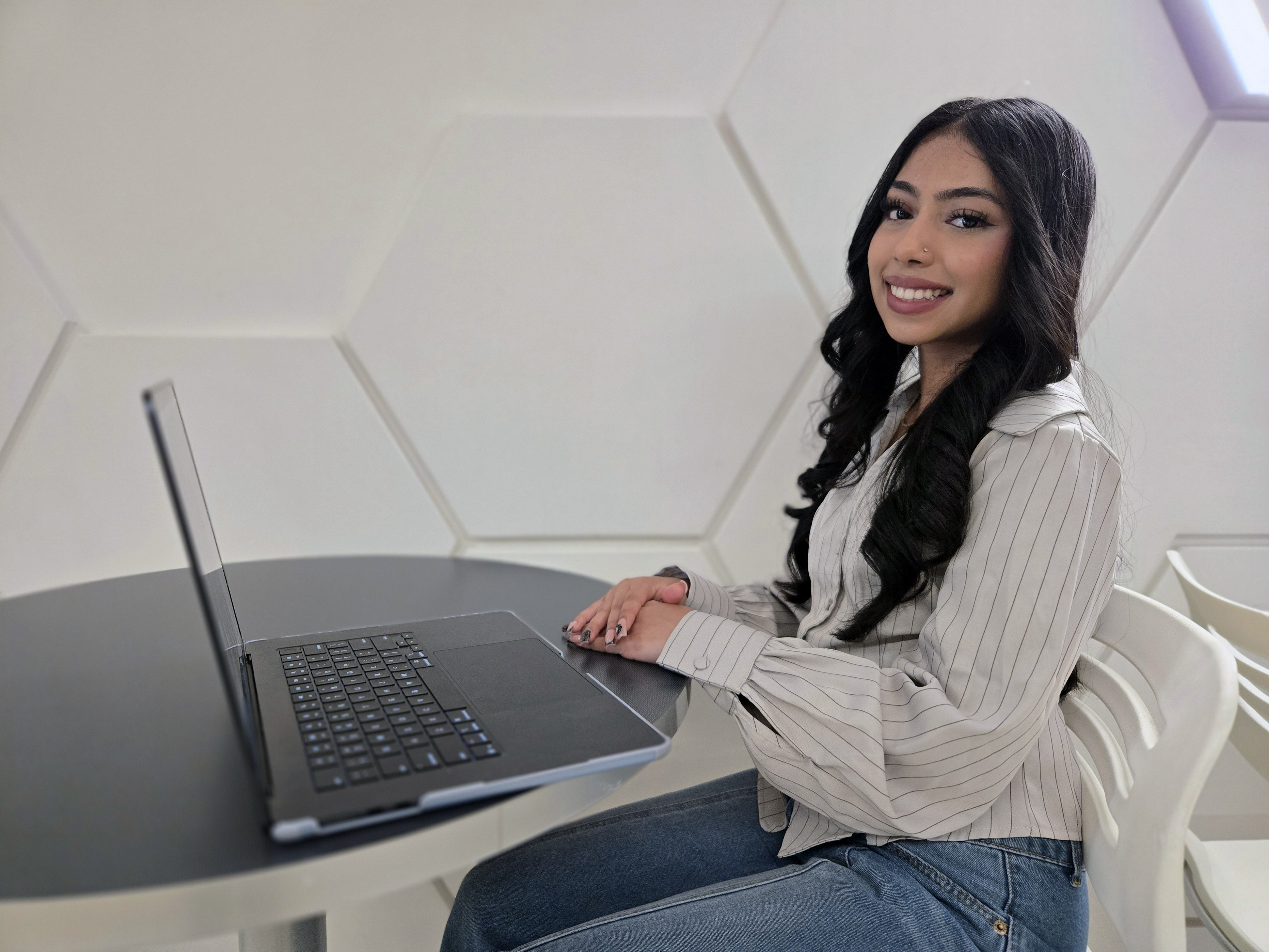 Hema Singh sitting at table with laptop in front of her