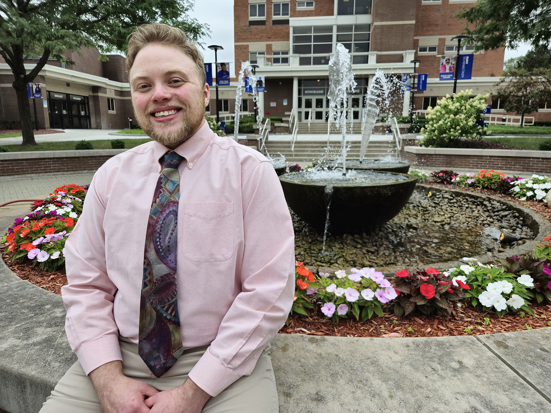 James Harris sitting outside in front of fountain, smiling