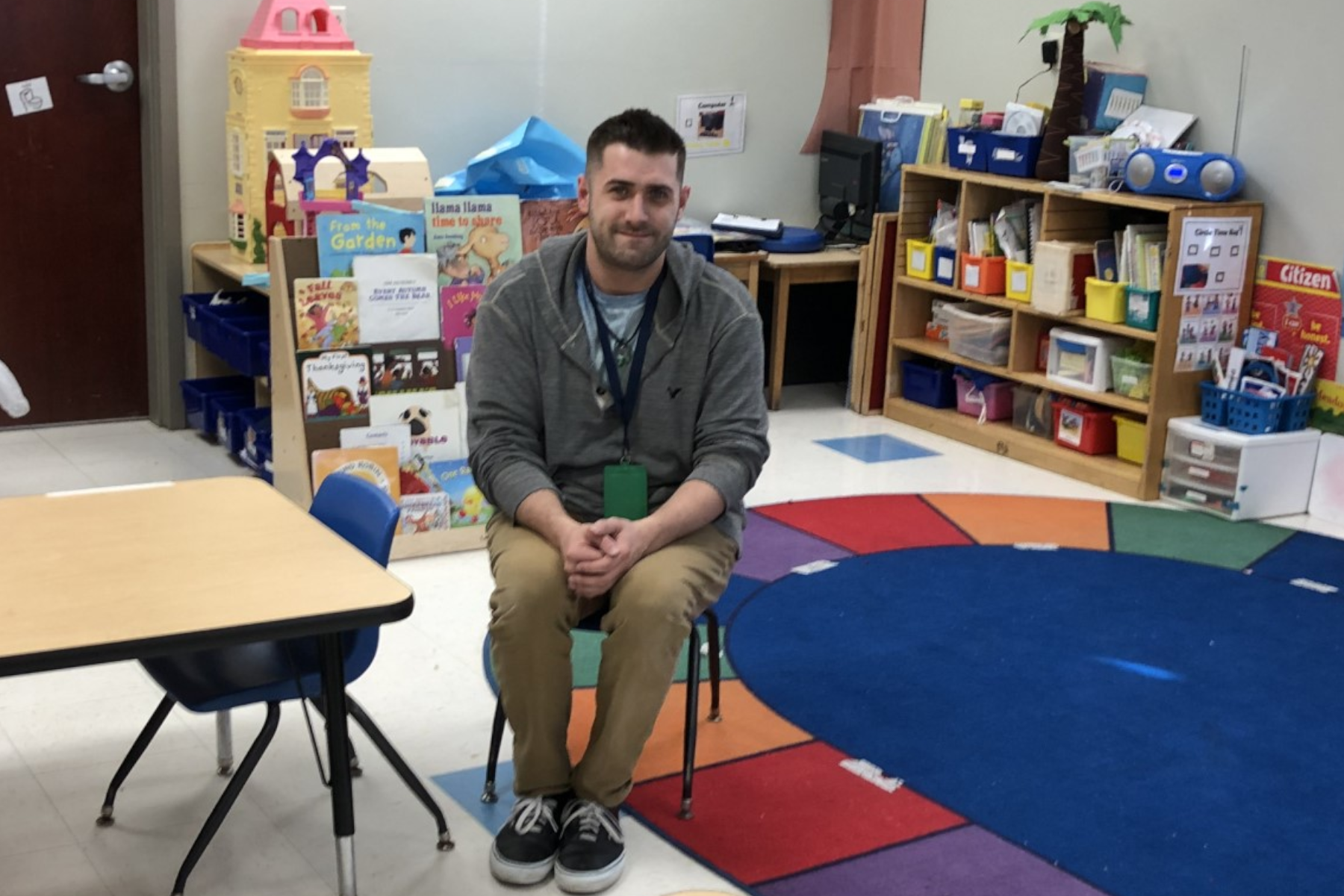 Josh Starr sitting in chair in preschool classroom.