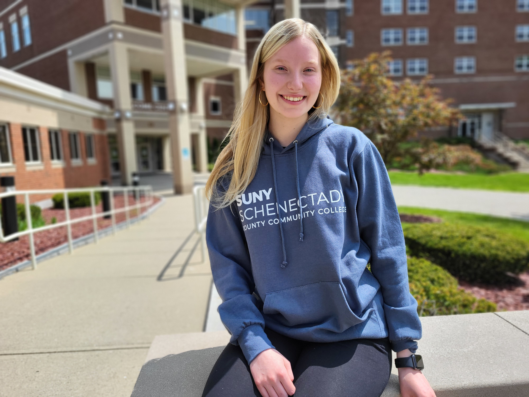 Lacey Allen sitting in the quad, sun shining, smiling