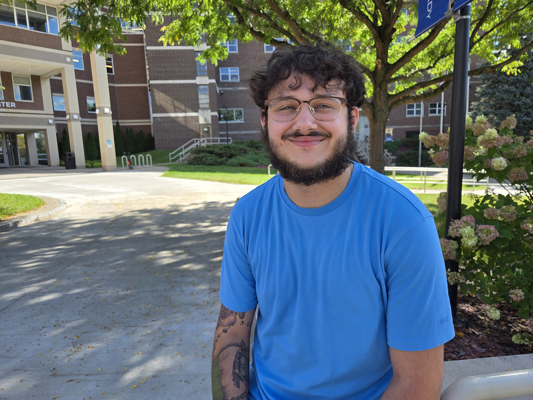 Matthew Perez, sitting outside in the Quad, smiling