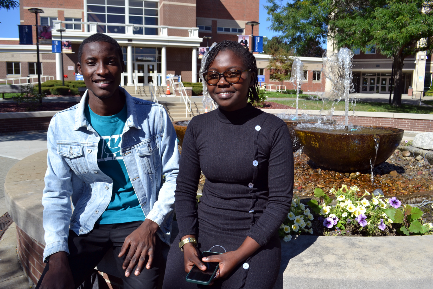 Maureen Mbanga and Ngambela Zulu sitting near fountain in the quad.