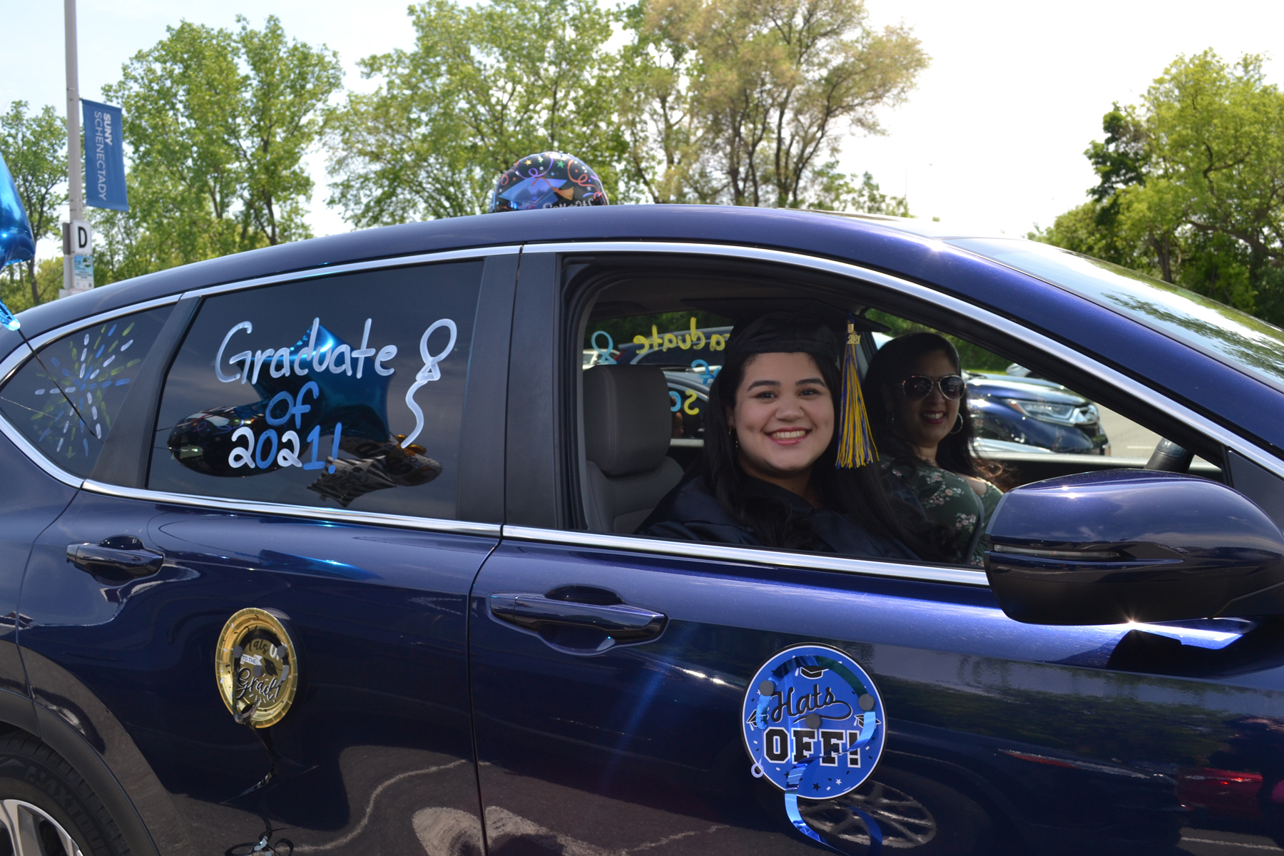 Melanie Ramos in cap and gown smiling in car.