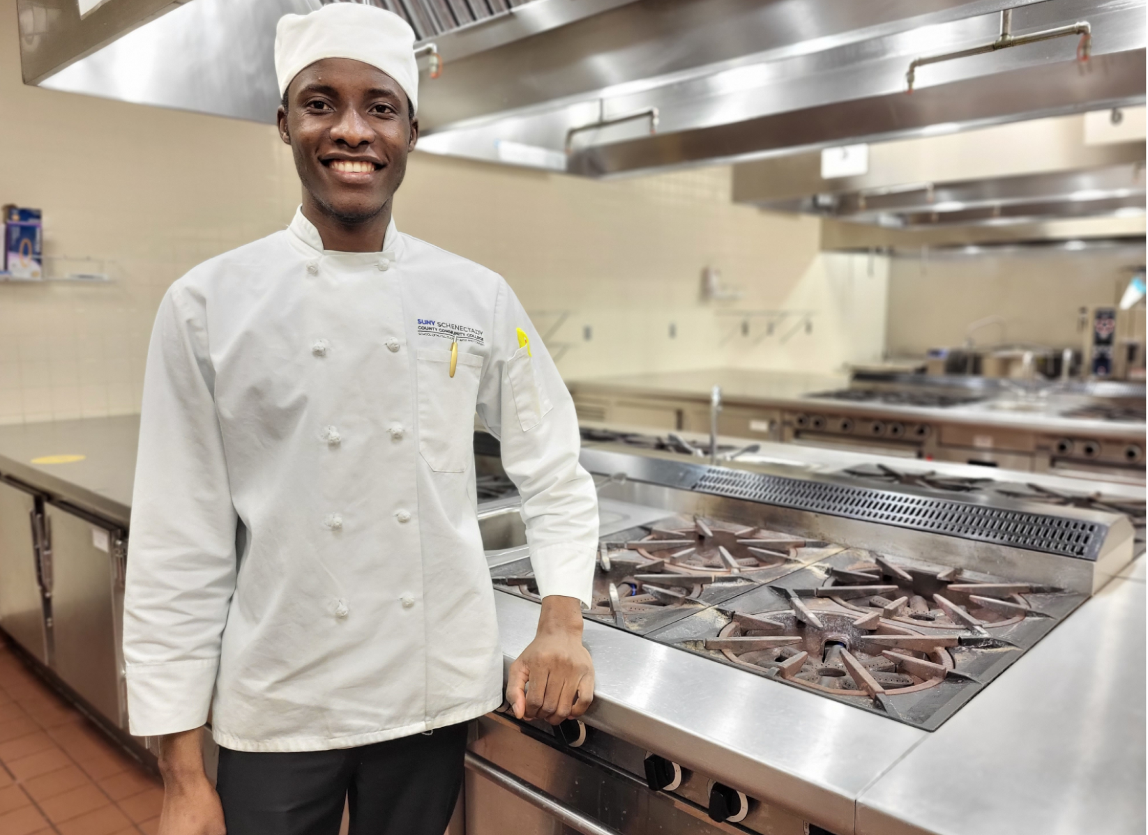 Ngambela  Zulu in chef's uniform standing in Culinary Arts Lab