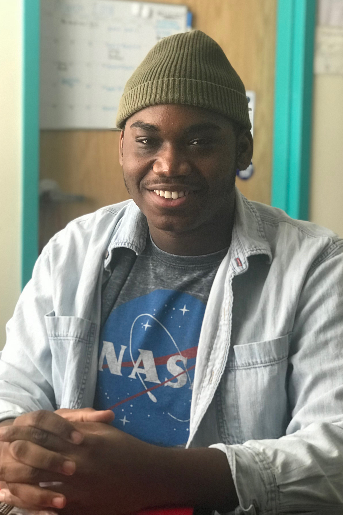 Nieem Crockett wearing hat, sitting, smiling