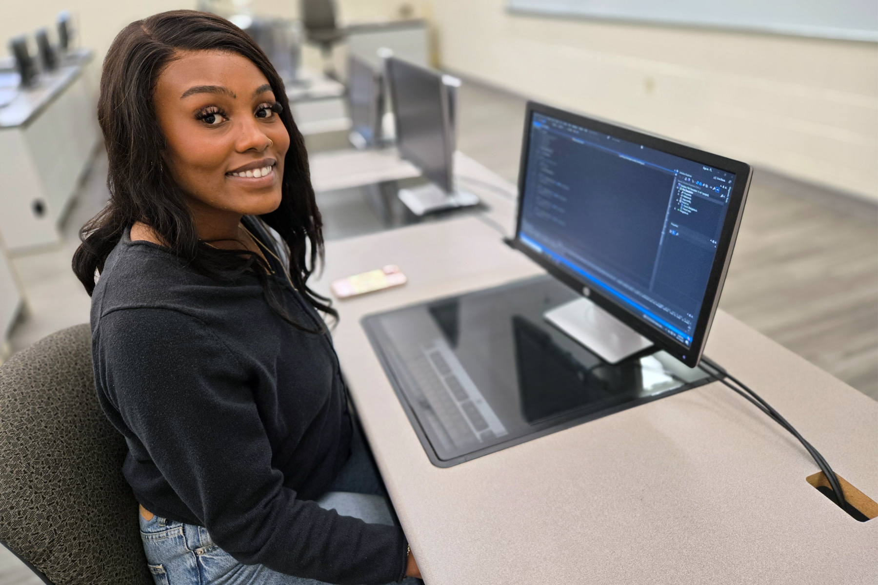 Olivia Edgar, in programming classroom, seated in front of computer