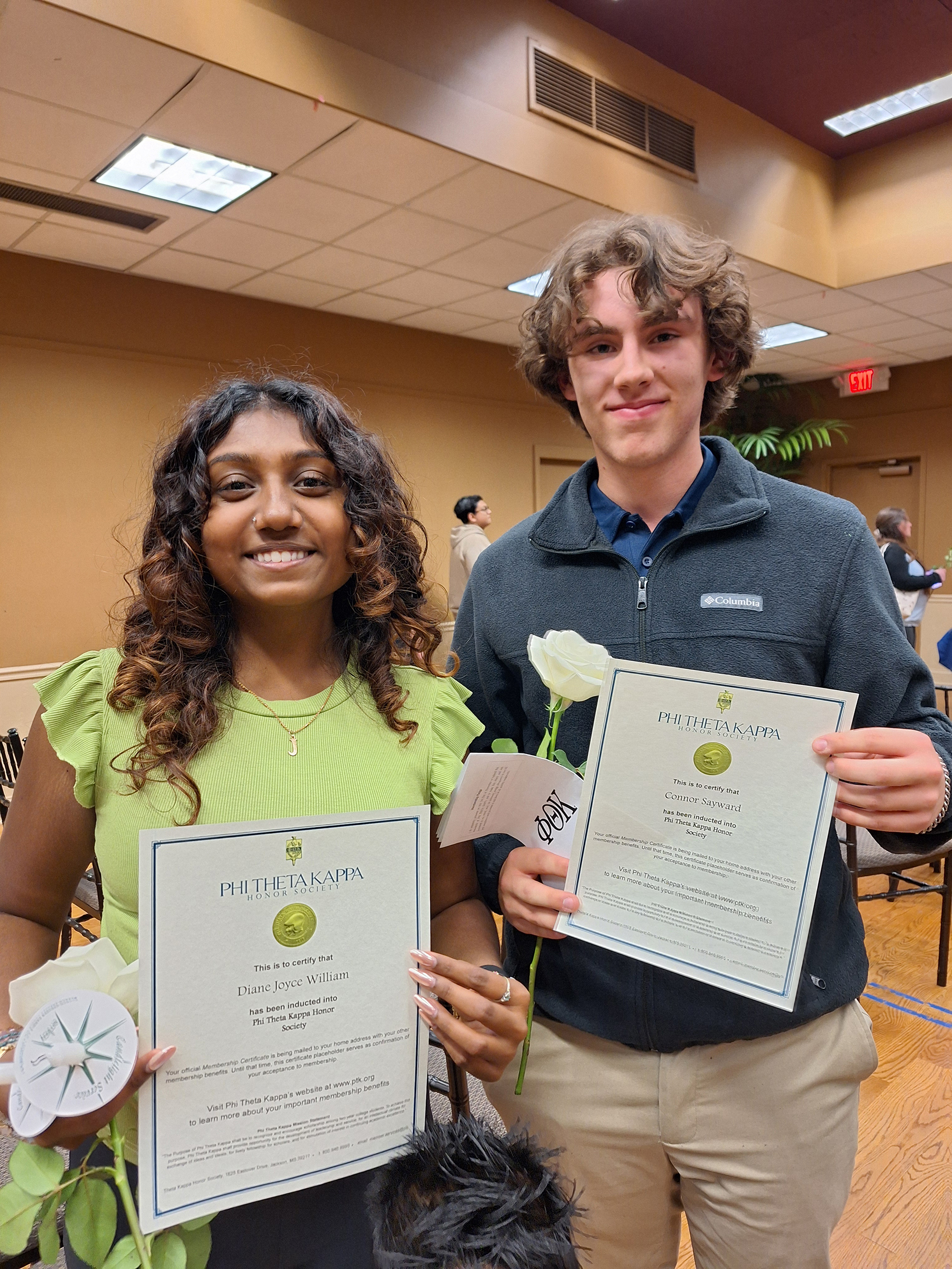 Two students standing, smiling, holding certificates